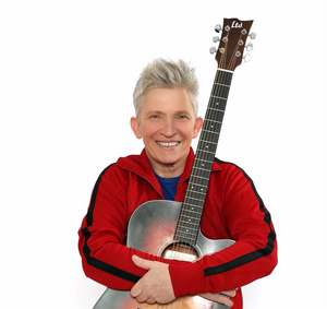 Die Musikerin Suli Puschban Die Musikerin Suli Puschban hält ihre Gitarre in den Armen und lacht.