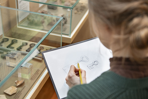 Eine Besucherin beim Zeichnen eines archäologischen Funds im Ausstellungsraum
