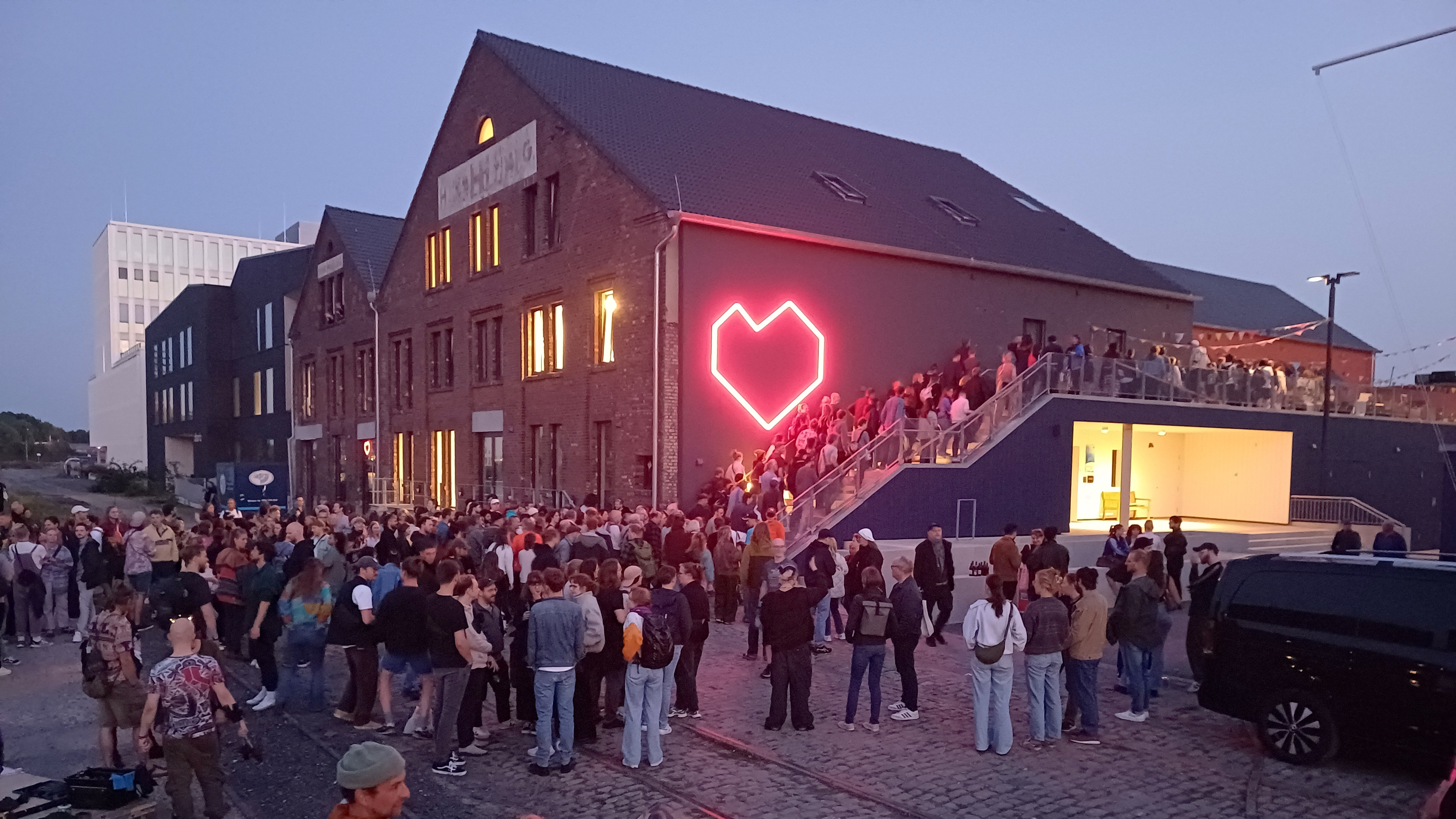 Bei der Eröffnung des B-Side Festivals 2024 warten viele Menschen in der Abenddämmerung auf Einlass. 