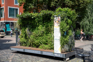 Mobiles grünes Zimmer mit dichtem Pflanzenbewuchs auf einem rollbaren Podest in einem städtischen Pflasterbereich