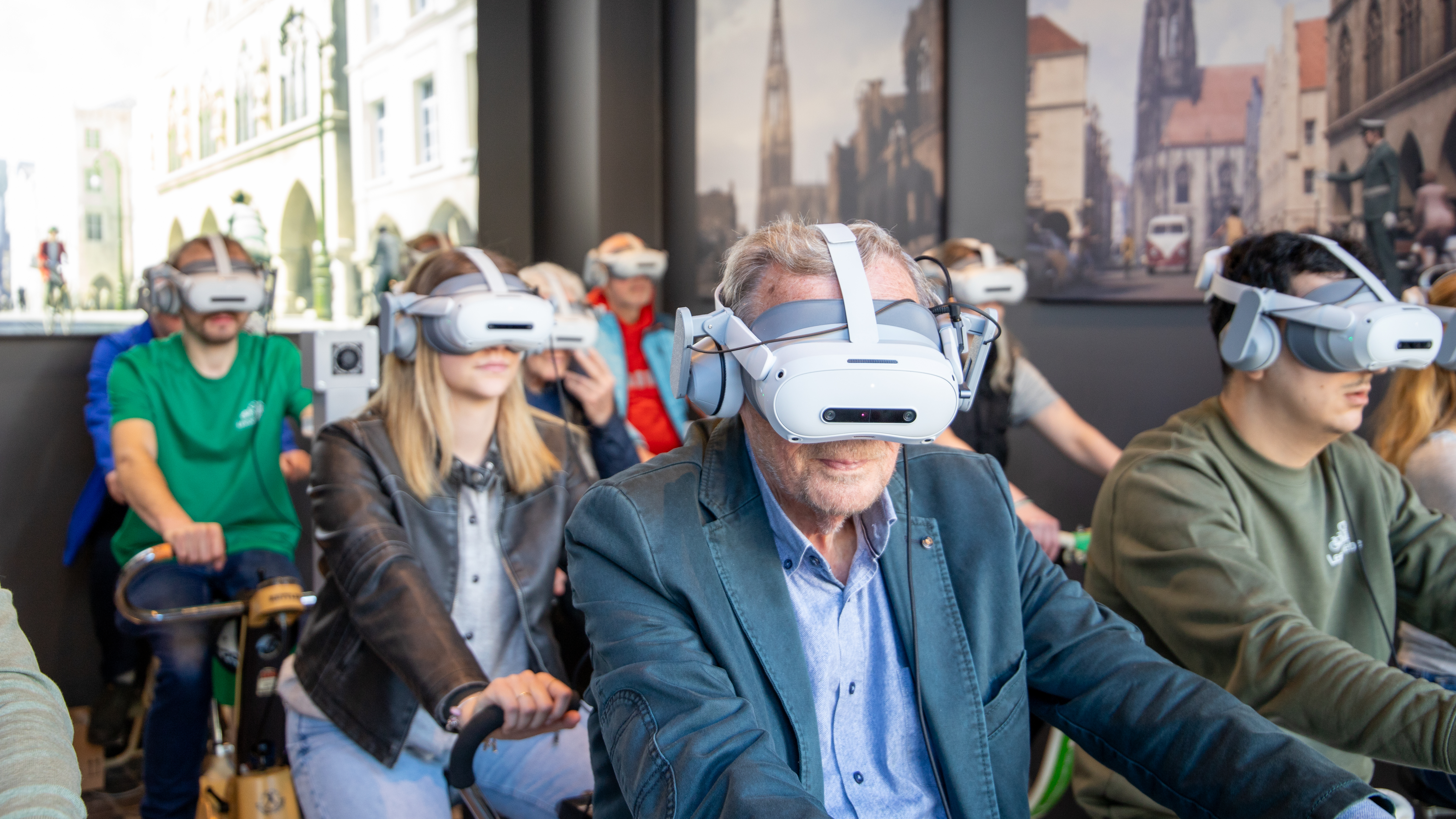 Teilnehmende sitzen auf Indoor-Fahrrädern und tragen eine VR-Brille im Leezodrom Münster.
