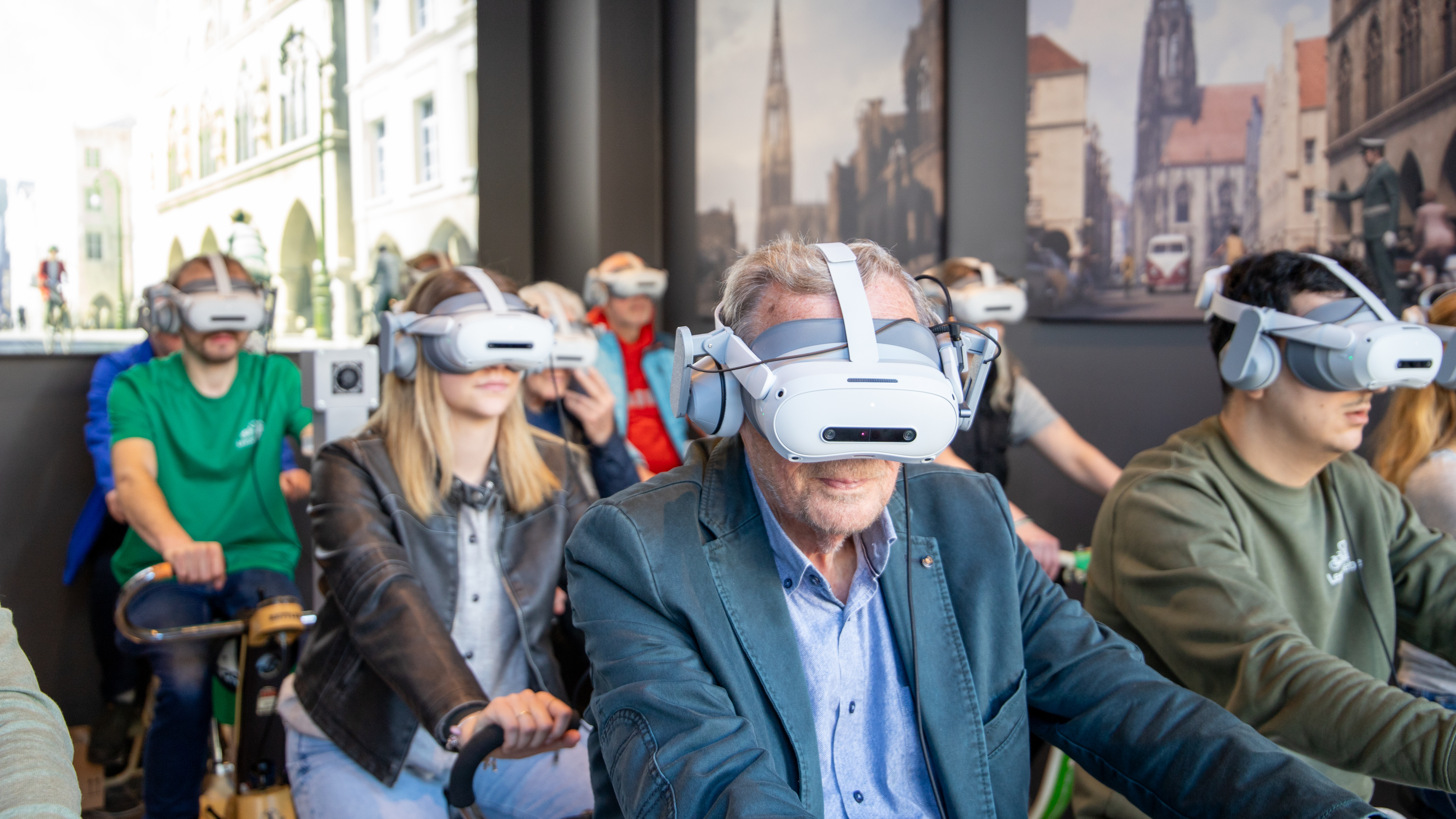 Teilnehmende sitzen auf Indoor-Fahrrädern und tragen eine VR-Brille im Leezodrom Münster.