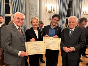 Gruppenfoto: vier Personen halten zwei Urkunden in der Hand und lächeln 
