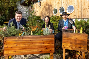 Drei Personen stehen hinter Hochbeeten