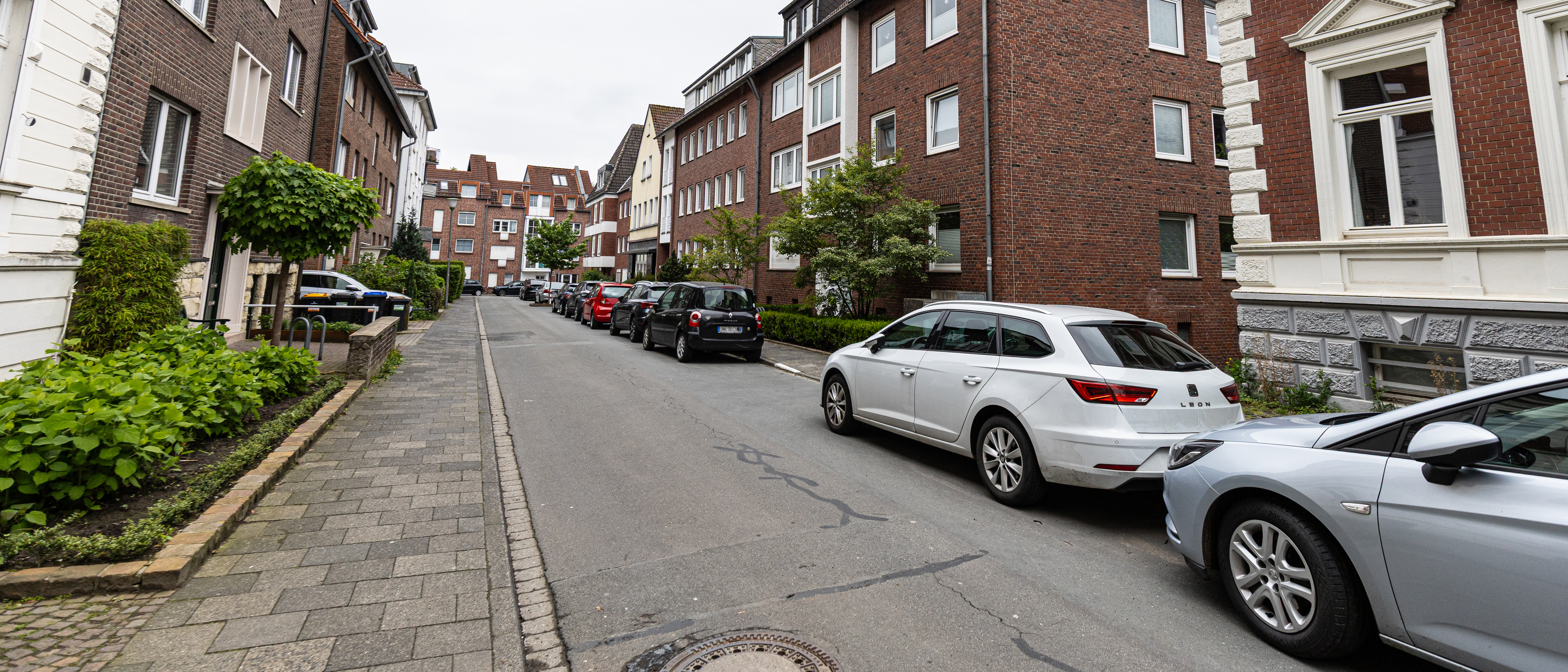 Blick in die Blumenstraße mit geparkten Autos am rechten Straßenrand