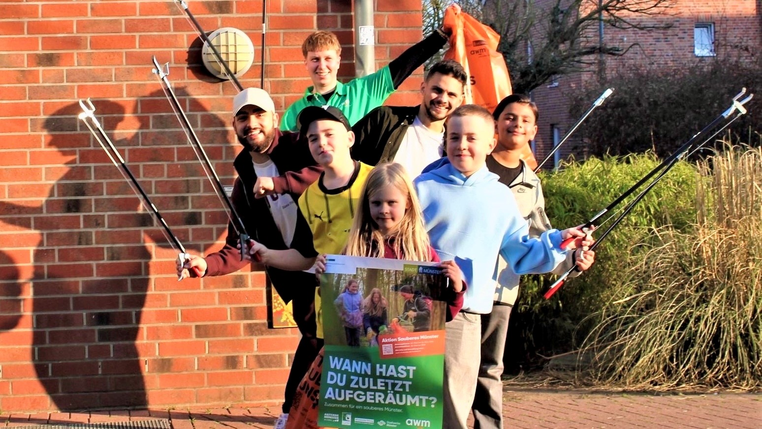 Gruppenbild mit Veranstaltungsplakat, Müllzangen und Müllbeuteln