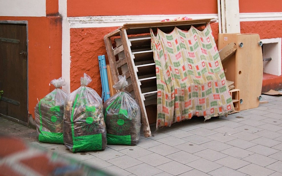 Sperrgut und Grünabfall-Säcke vor einem Wohnhaus.