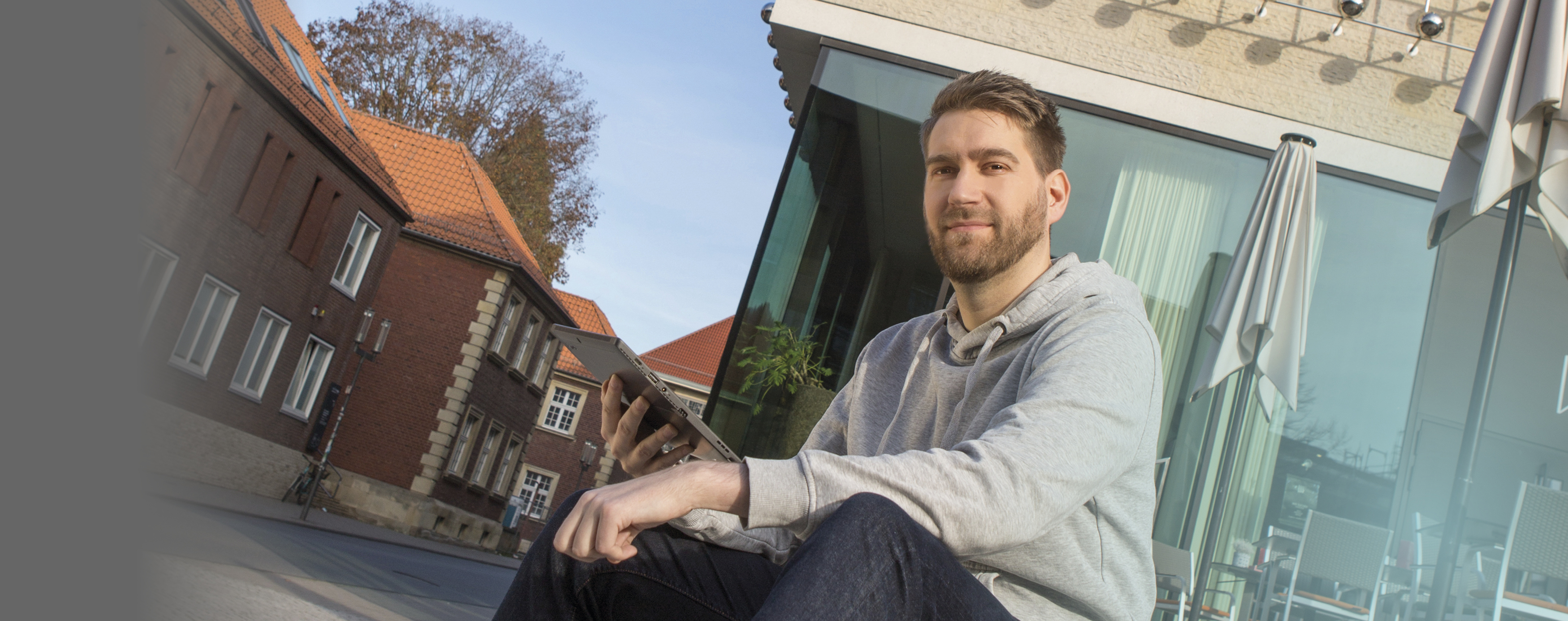 Ein Mitarbeiter der citeq sitzt auf der Treppe vor dem LWL-Museum und kann dank seines Tablet von dort aus arbeiten