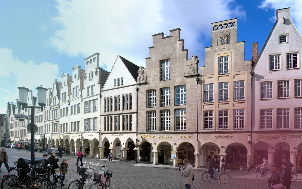 Eine Häuserreihe, die die historisch rekonstruierten Fassaden des kopfsteingepflasterten Prinzipalmarktes in Münster zeigt.