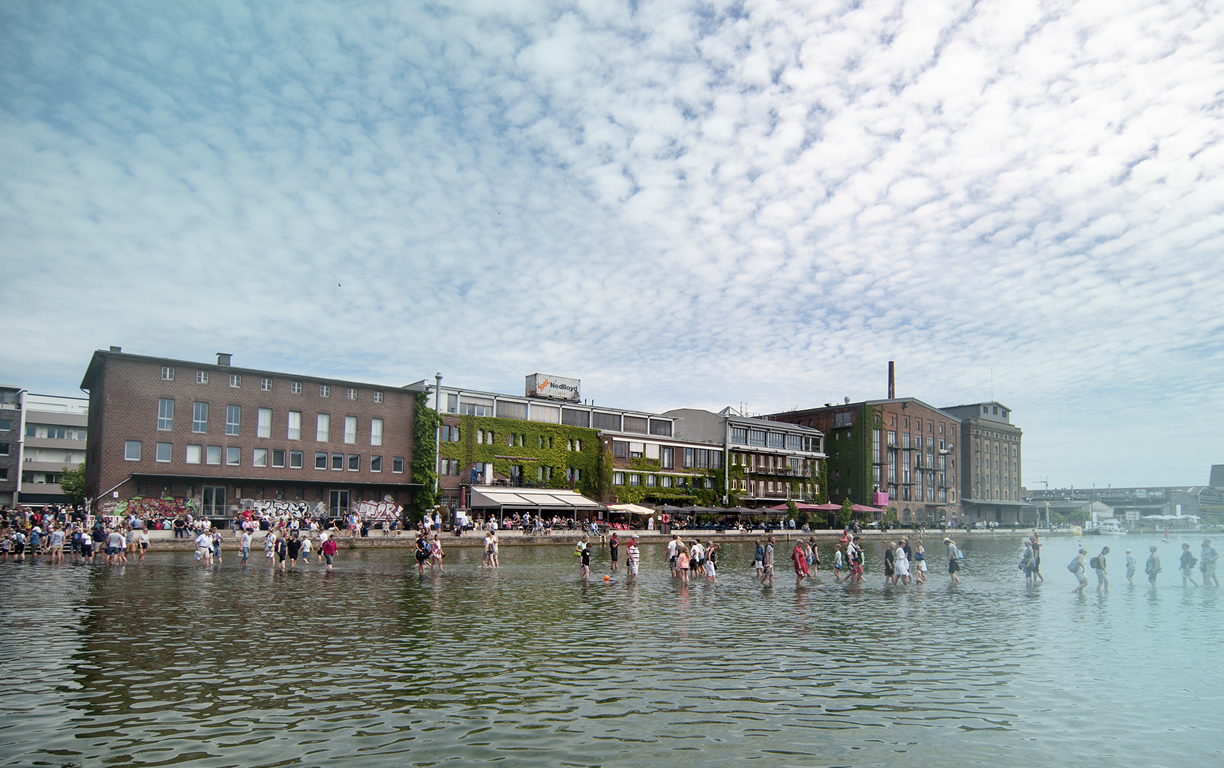 Menschen gehen im Hafen von Münster über einen knapp unter Wasser befindlichen Steg bei einem Skulptur-Projekt 2017.