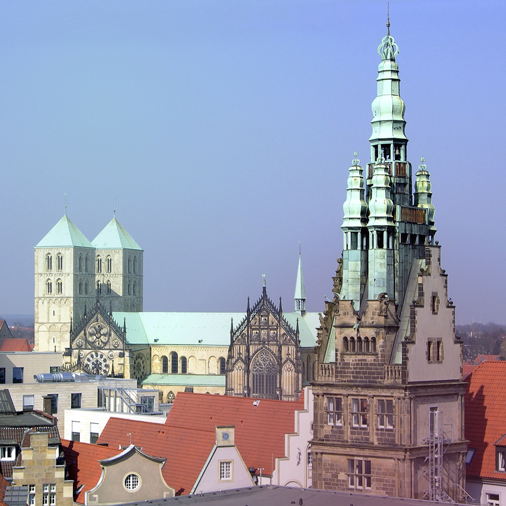 Ein Blick von oben auf die Stadt Münster mit dem Rathausturm im Vordergrund und dem Dom im Hintergrund.