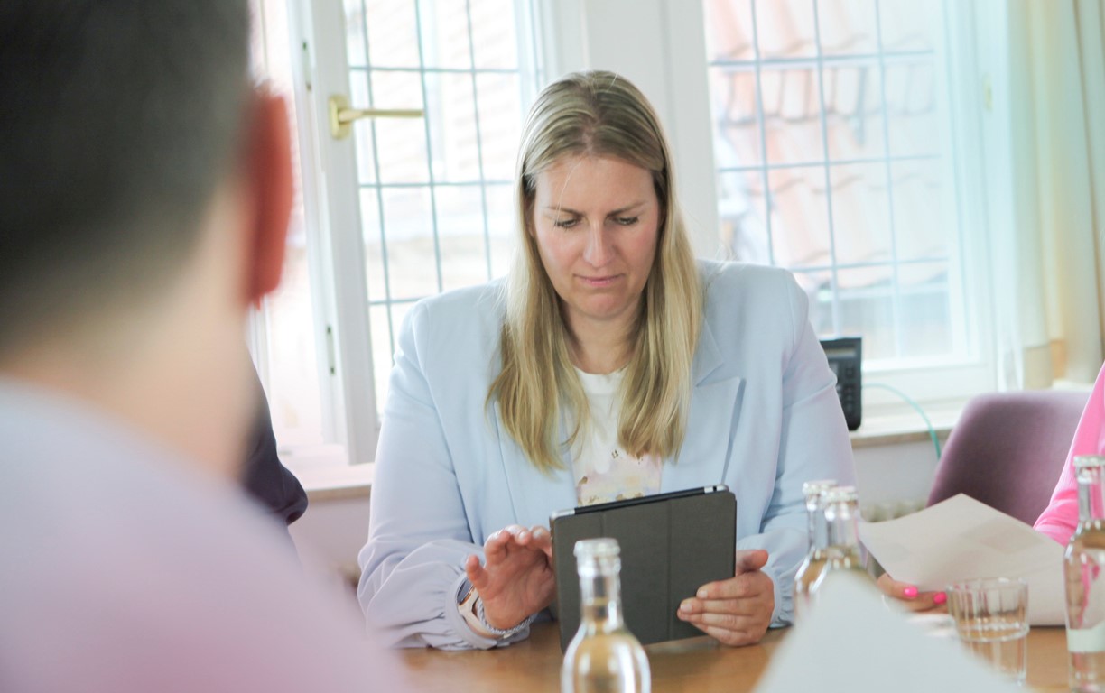 Eine Person sitzt mit einer Frau von der Stadt in einem Bewerbungsgespräch, welche sich  auf ihrem Tablet Notizen macht.