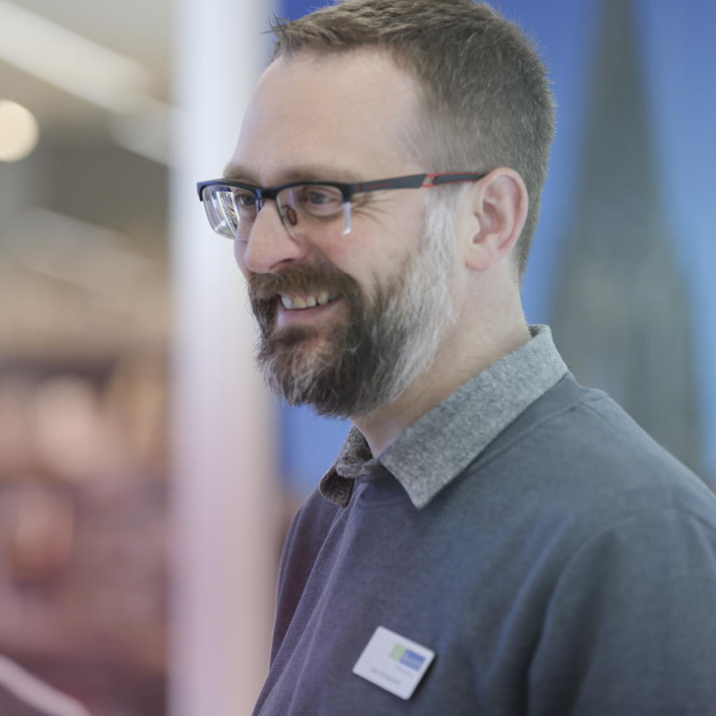 Ein Mann mit Brille befindet sich in einem Gespräch und lacht herzhaft zu seinem Gesprächspartner.