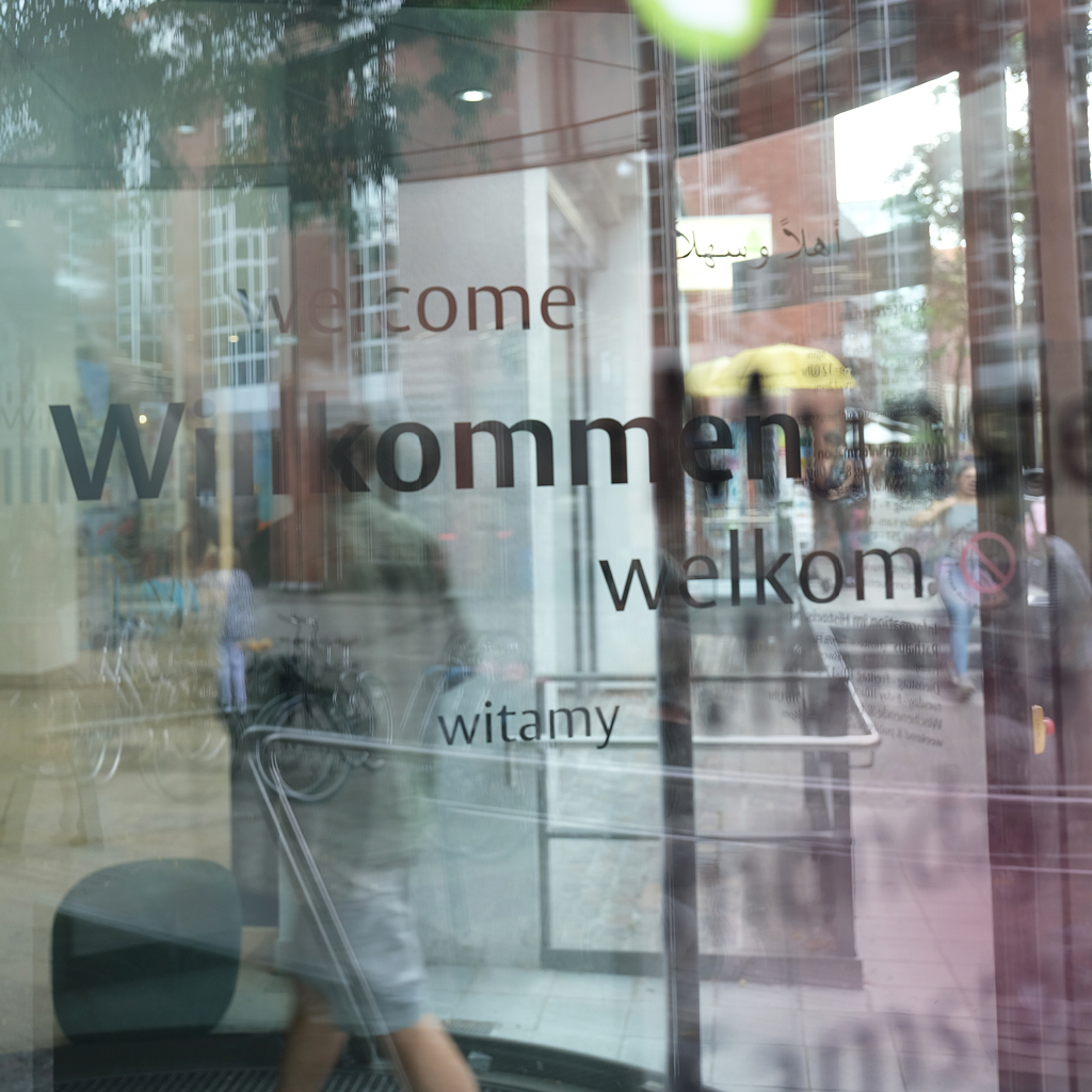 Eine Drehtür vor dem Stadthaus eins dreht sich mit der Aufschrift 'Willkommen'.