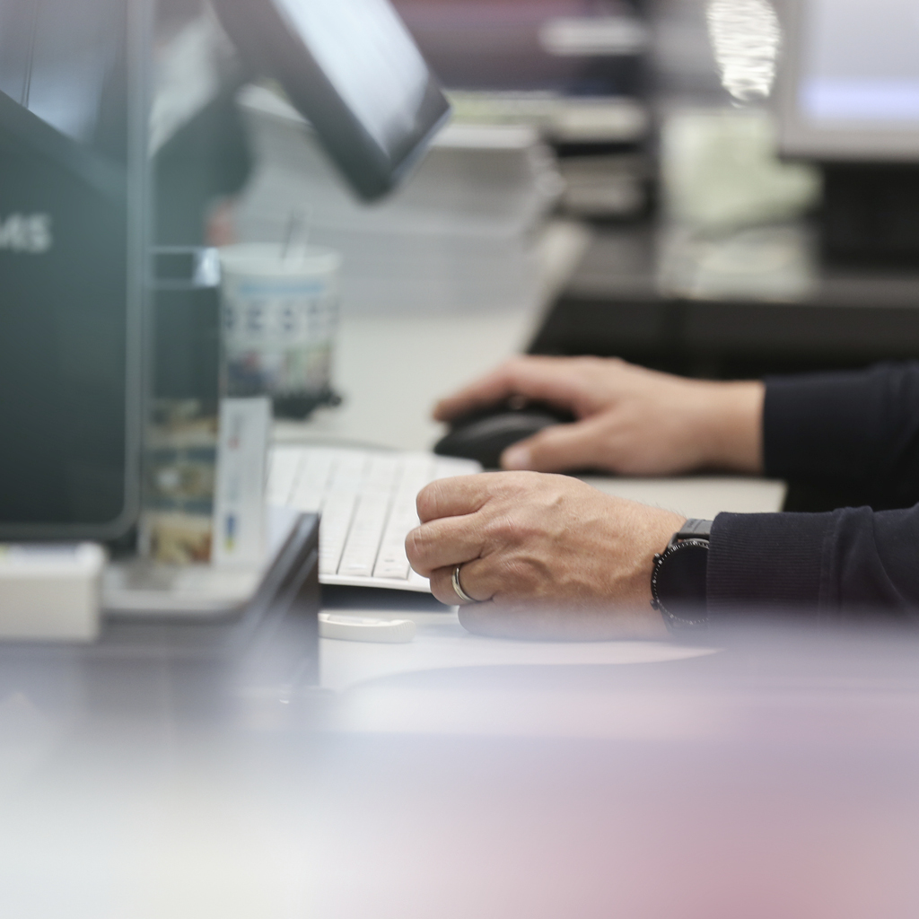 Eine Person sitzt an einem Computer und arbeitet daran mit einer Computermaus.