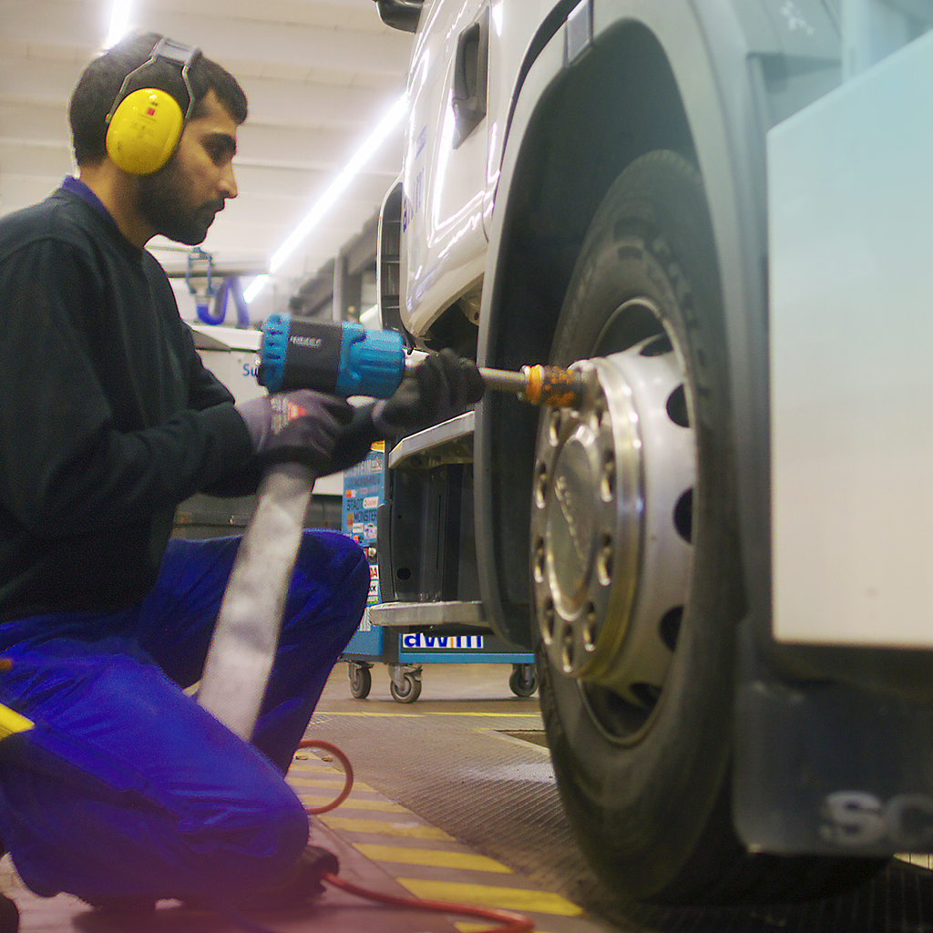 Ein männlicher Werkstattarbeiter ist dabei, einen Reifenwechsel an einem Abfallsammelfahrzeug zu vollziehen.
