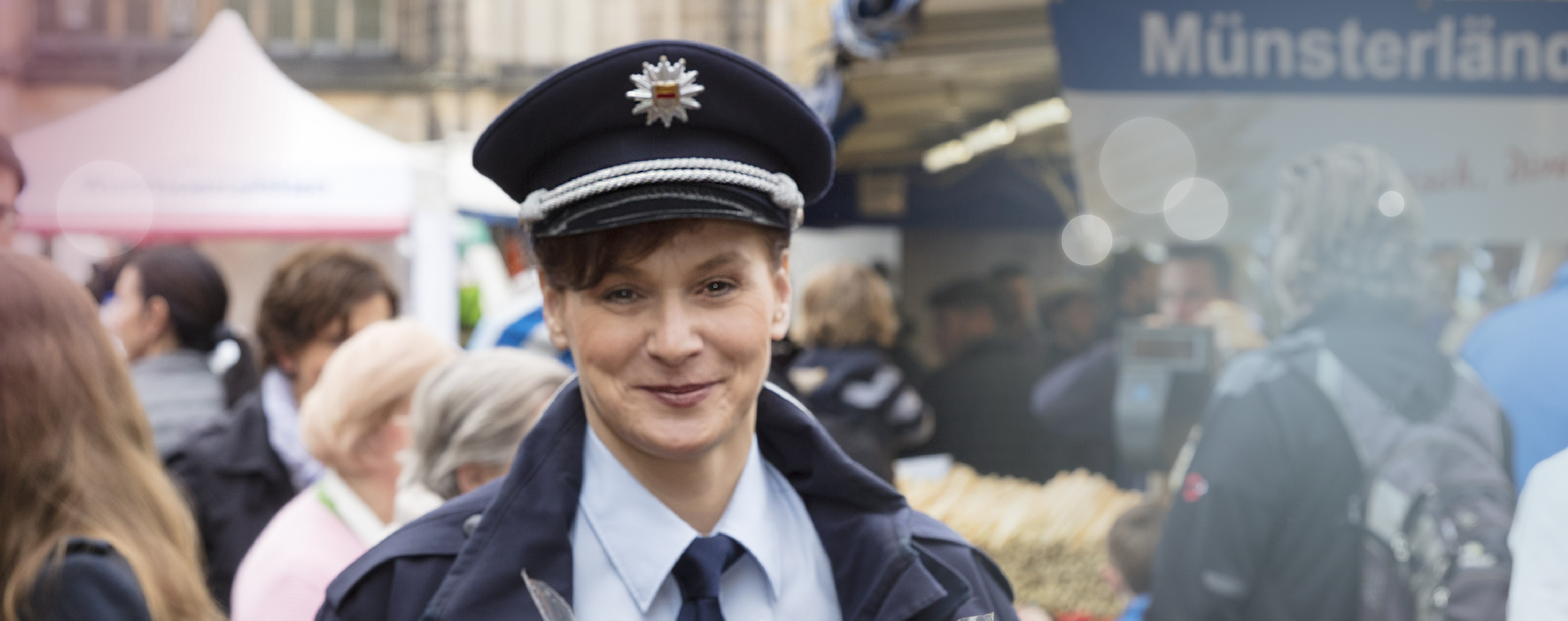 Vor einer Menschenmenge auf dem Stadtfest steht eine uniformierte Mitarbeiterin des Ordnungsamtes und lächelt in die Kamera.