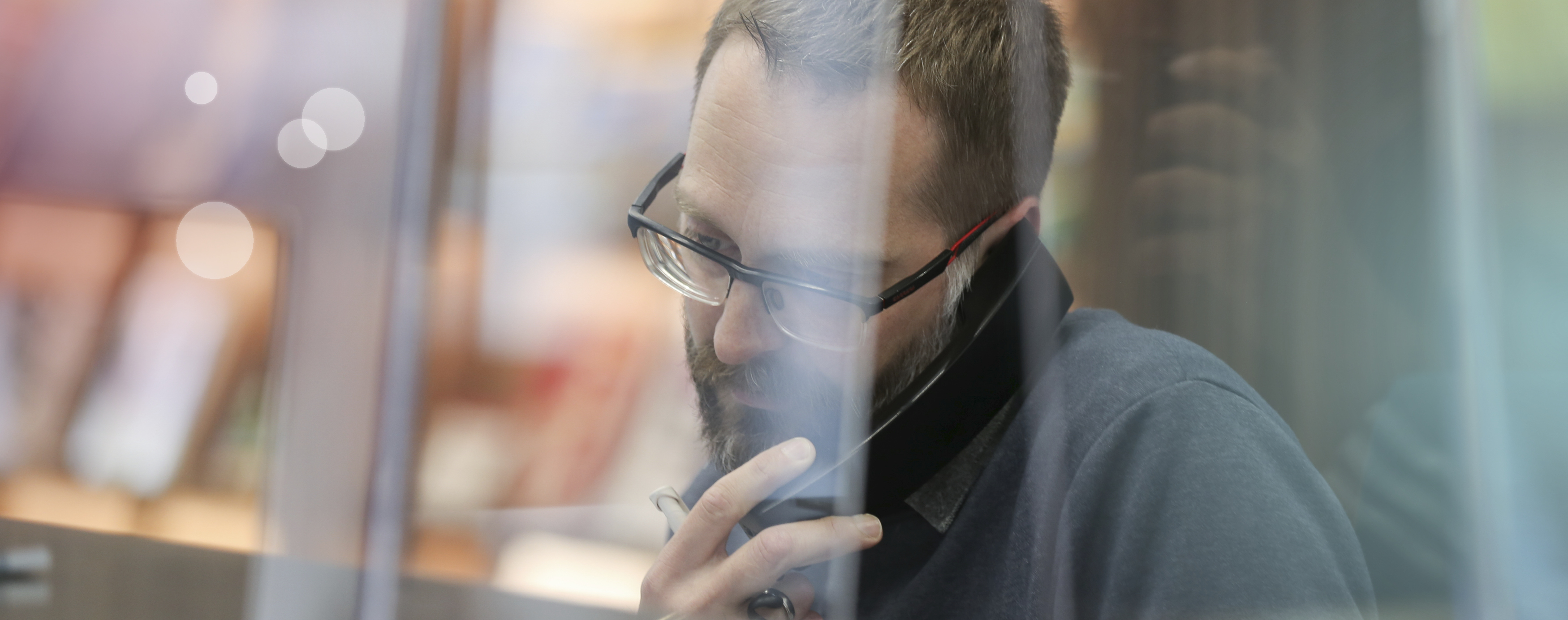 Ein Mitarbeiter der Stadt sitzt hinter einer Glasscheibe und telefoniert konzentriert.