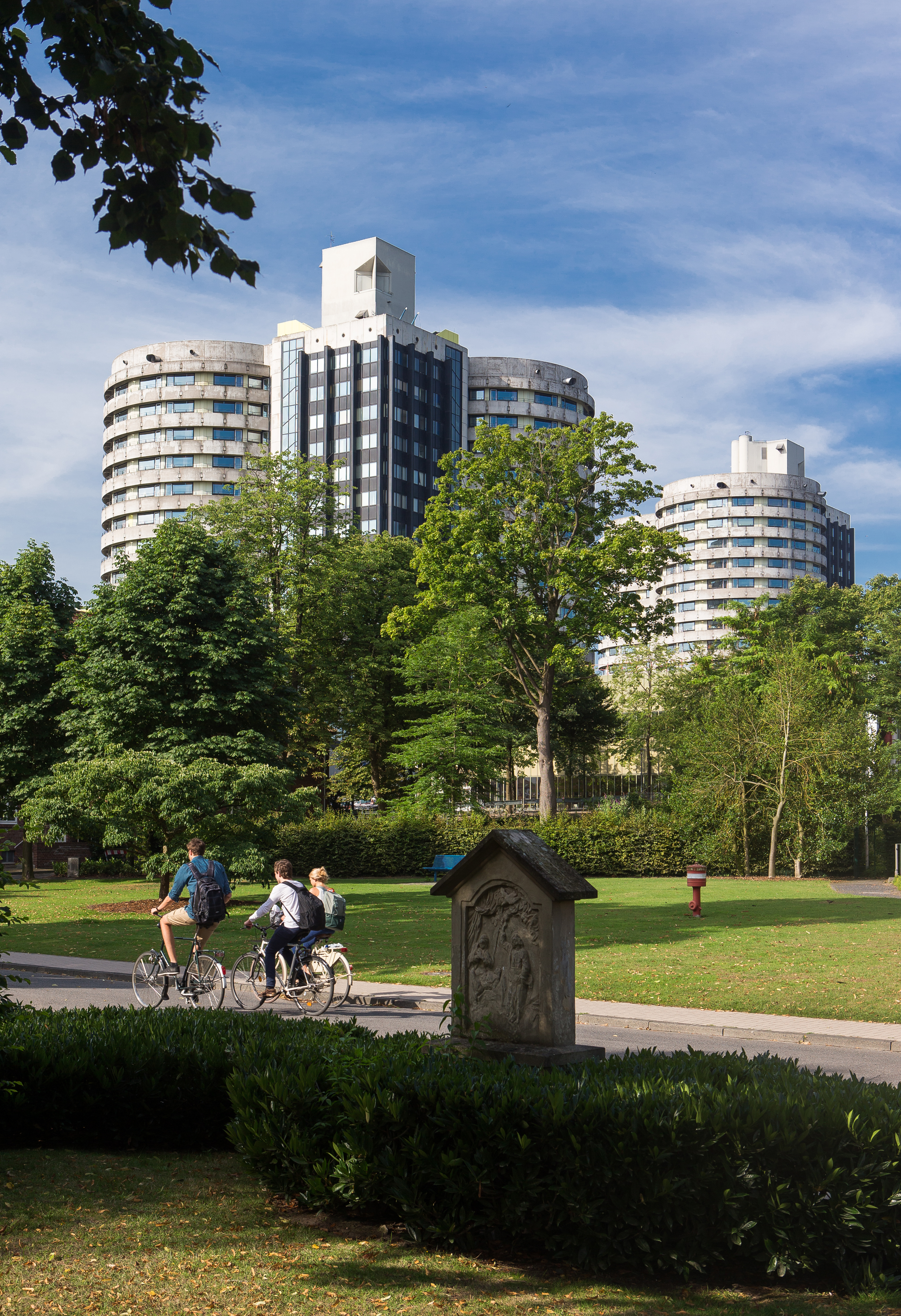Zwei Hochhäuser im Hintergrund, davor ein Park mit Radler*innen uaf einem Fahrradweg