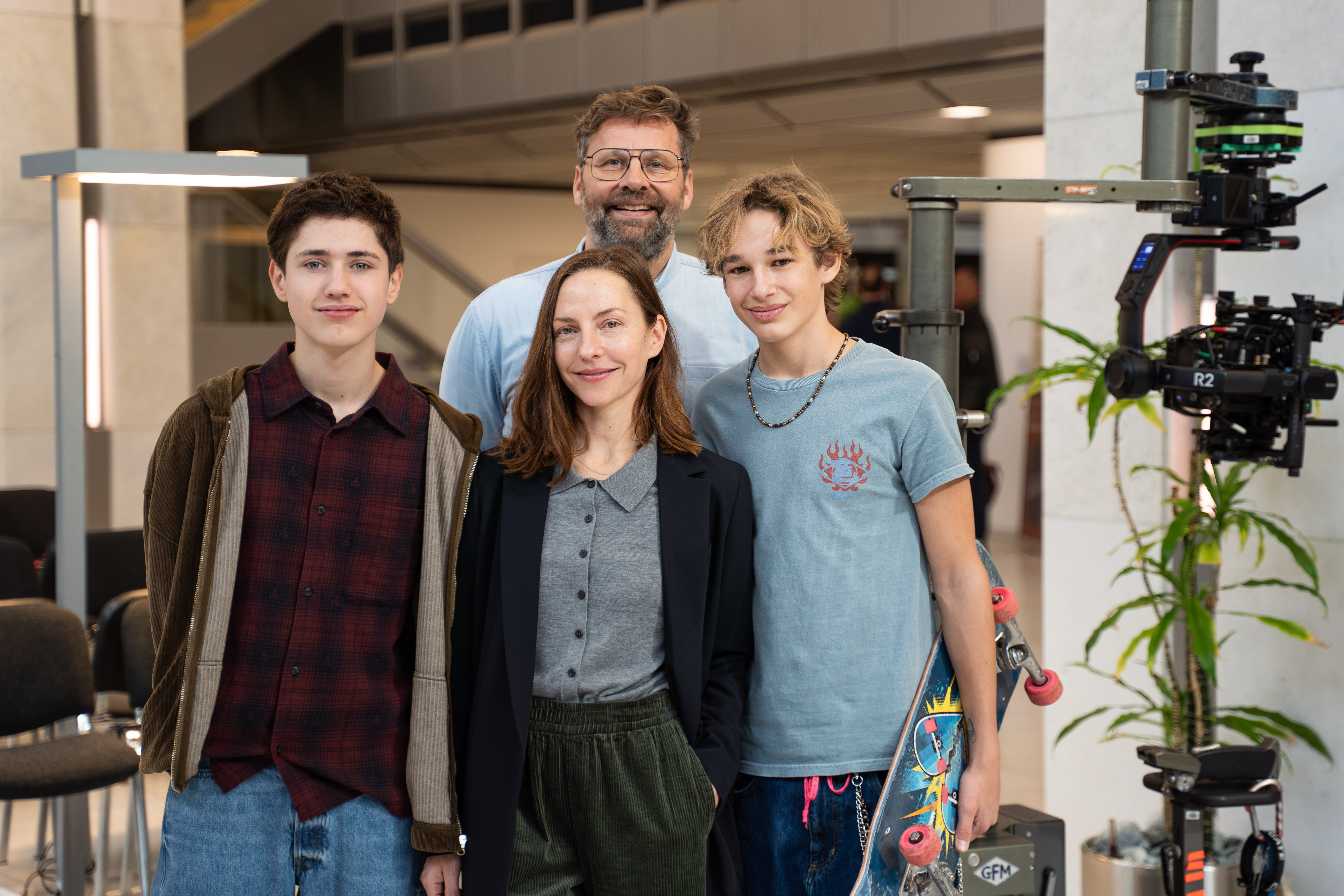 Vier Personen stehen in einem Foyer und posieren für ein Gruppenfoto.
