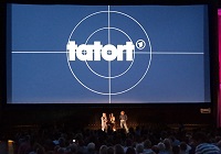 Tatort Münster Open Air 2016: Große Leinwand mit Tatort-Logo, davor Publikum im Dunklen, auf der Bühne drei Menschen.