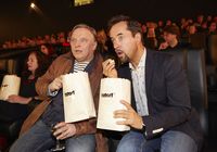Axel Prahl und Jan Josef Liefers sitzen mit Popcorntüten in der ersten Kino-Reihe bei der Kinopremiere des 25. Münster-Tatort "Der Hammer" 2014 im Cineplex-Kino Münster. Foto: WDR/Claus Langer