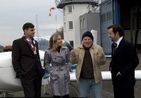 Vier Schauspieler vor einem Flugzeug auf dem Flugplatz