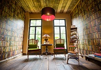 Zimmer mit zwei Sesseln, Büchern und Bücher-Tapeten an den Wänden
