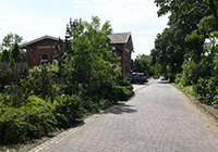 Der alte Bahnhof Reken  - rot geklinkertes altes Bahnhofsgebäude, zwischen grünen Bäumen und Gleisen