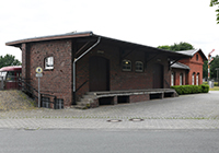 Alter Bahnhof Lette - Außenansicht, ein dunkel geklinkerter Schuppen mit Rampe, rechts daneben ein heller geklinkertes einstöckiges Bahnhofsgebäude