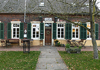 Eingang der Höltn'nen Schluse am Max Clemens-Kanal: Durch einen Garten schaut man auf eine alte Tür.