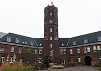 Rotes Backsteingebäude mit mittigem Turm auf dem Alexianer-Campus