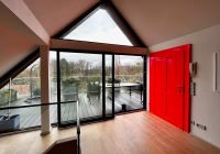Blick aus einem kaum eingerichteten Raum mit rotgestrichener Tür  auf eine große Dachterasse