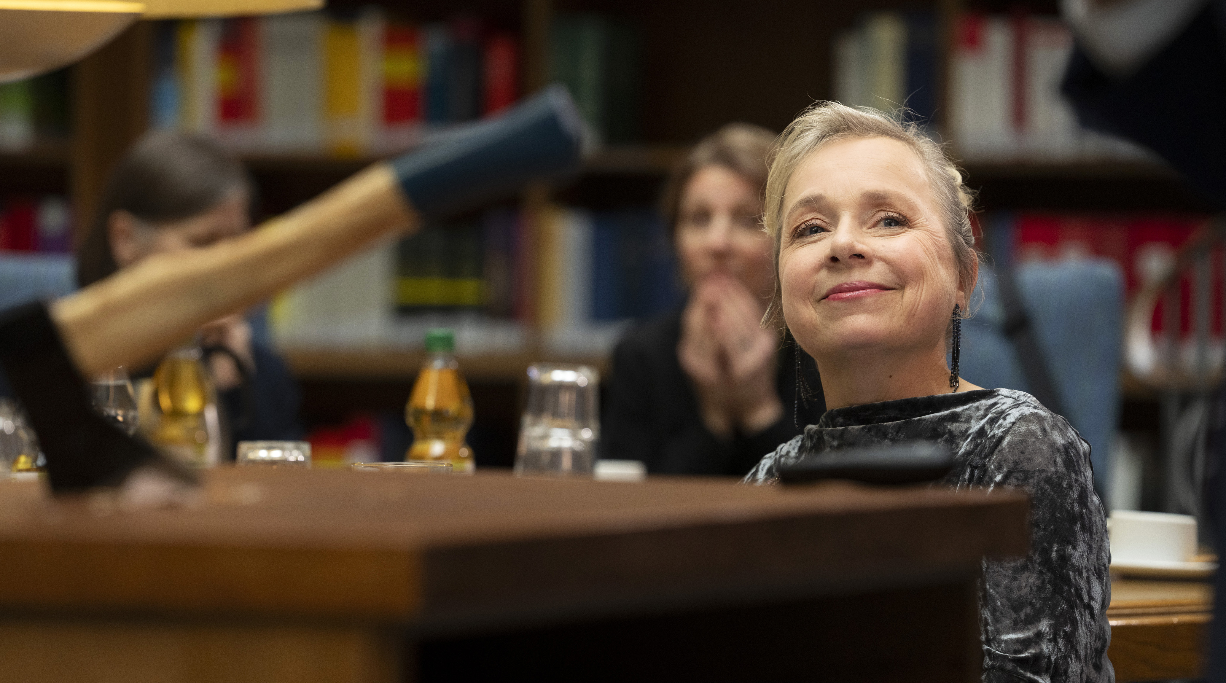 Silke Haller (Christine Urpruch) amüsiert sich über Dr. Boernes eindringliche Darstellung der Betrugsmaschen und seine dramatische Demonstration beim Seminar über Versicherungsbetrug. 