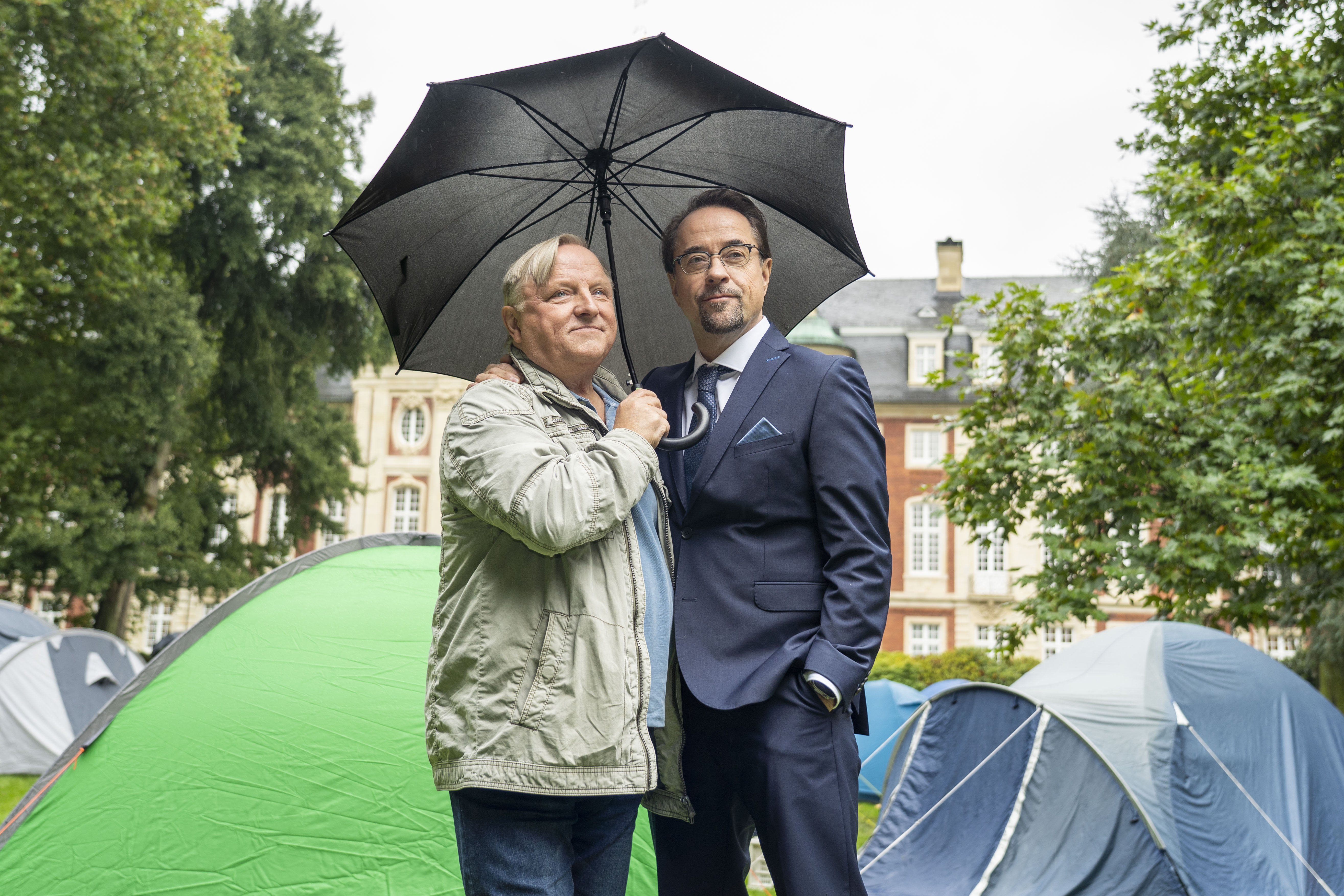 Prahl und Liefers stehen vor Zelten hinter dem Schloss Münster