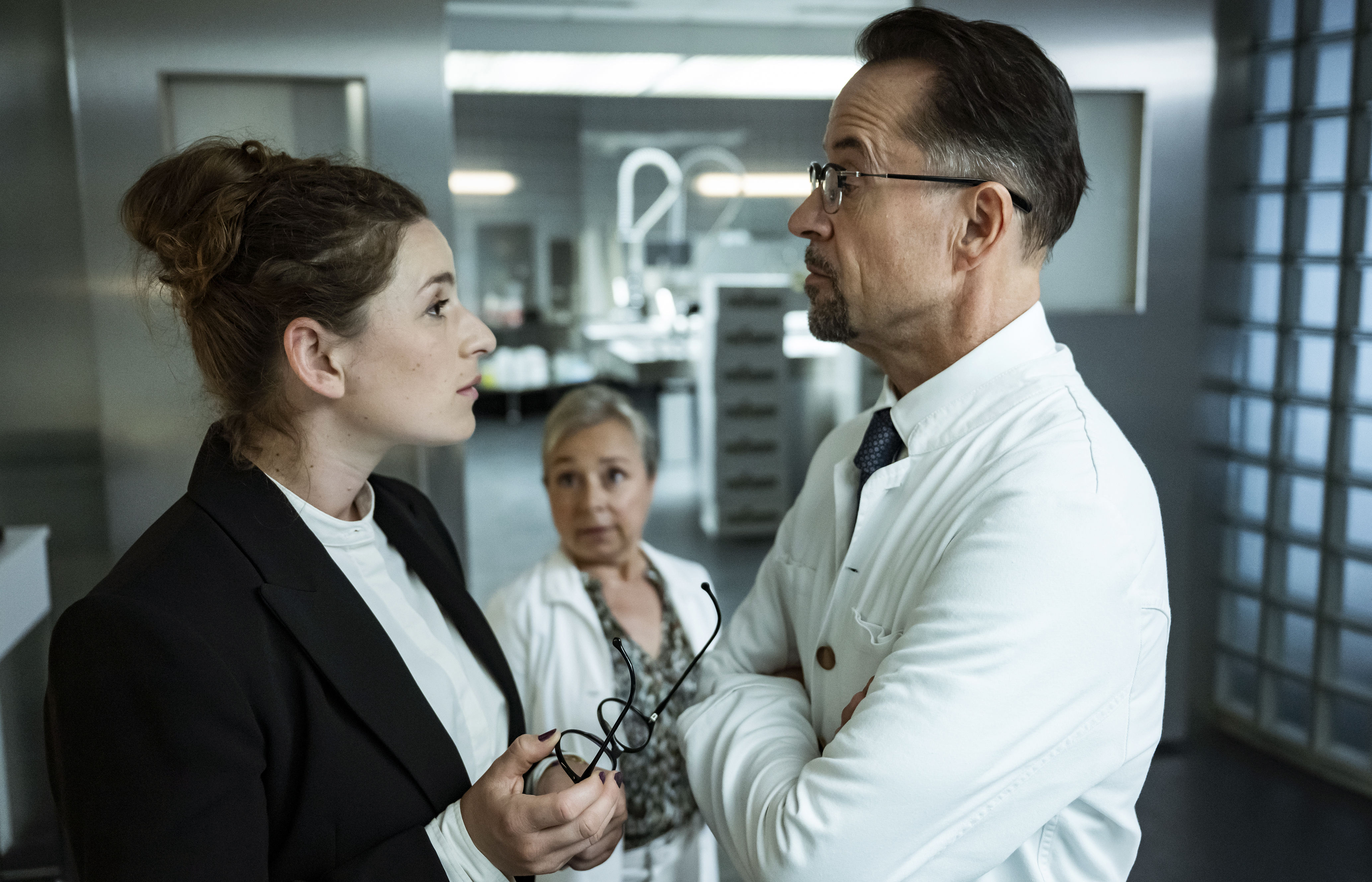 Staatsanwältin Nicole König (Lou Strenger) beauftragt Prof. Boerne (Jan Josef Liefers, r.) zu seinem Missfallen mit der Untersuchung der sichergestellten Bonbons - Silke Haller (ChrisTine Urspruch, M.) mag das resolute Auftreten der jungen Frau.