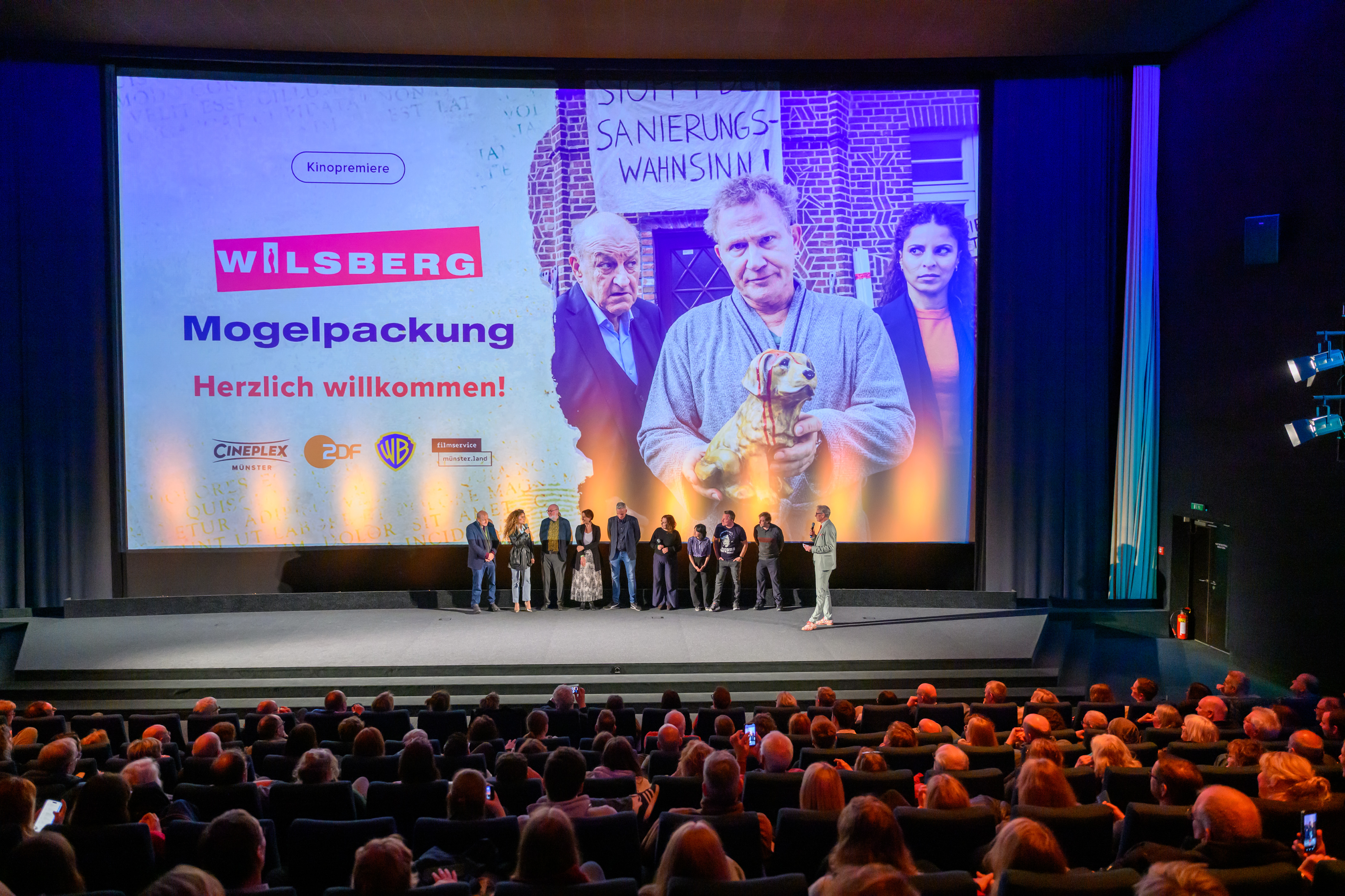 Blick aus dem Publikum auf die Bühne mit Filmteam im Interview mit Moderator Adam Riese