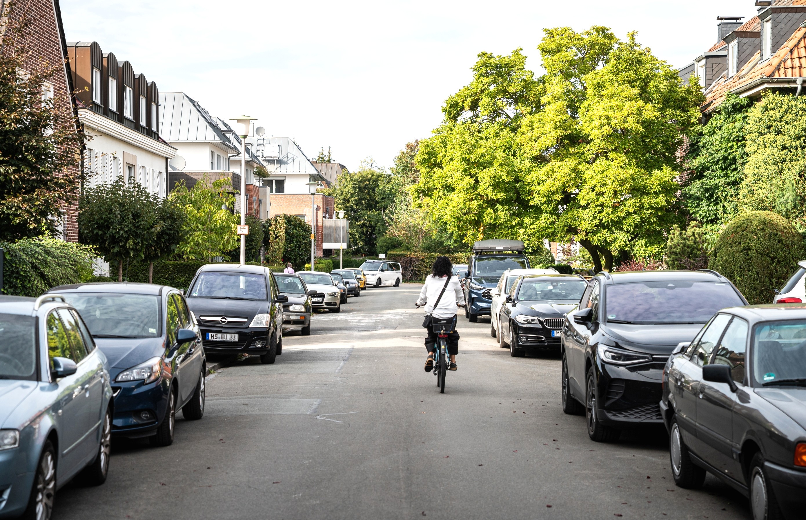 Die Elisabet-Ney-Straße: Beide Seiten sind mit Autos zugeparkt. Ein Radfahrer fährt die Straße entlang.