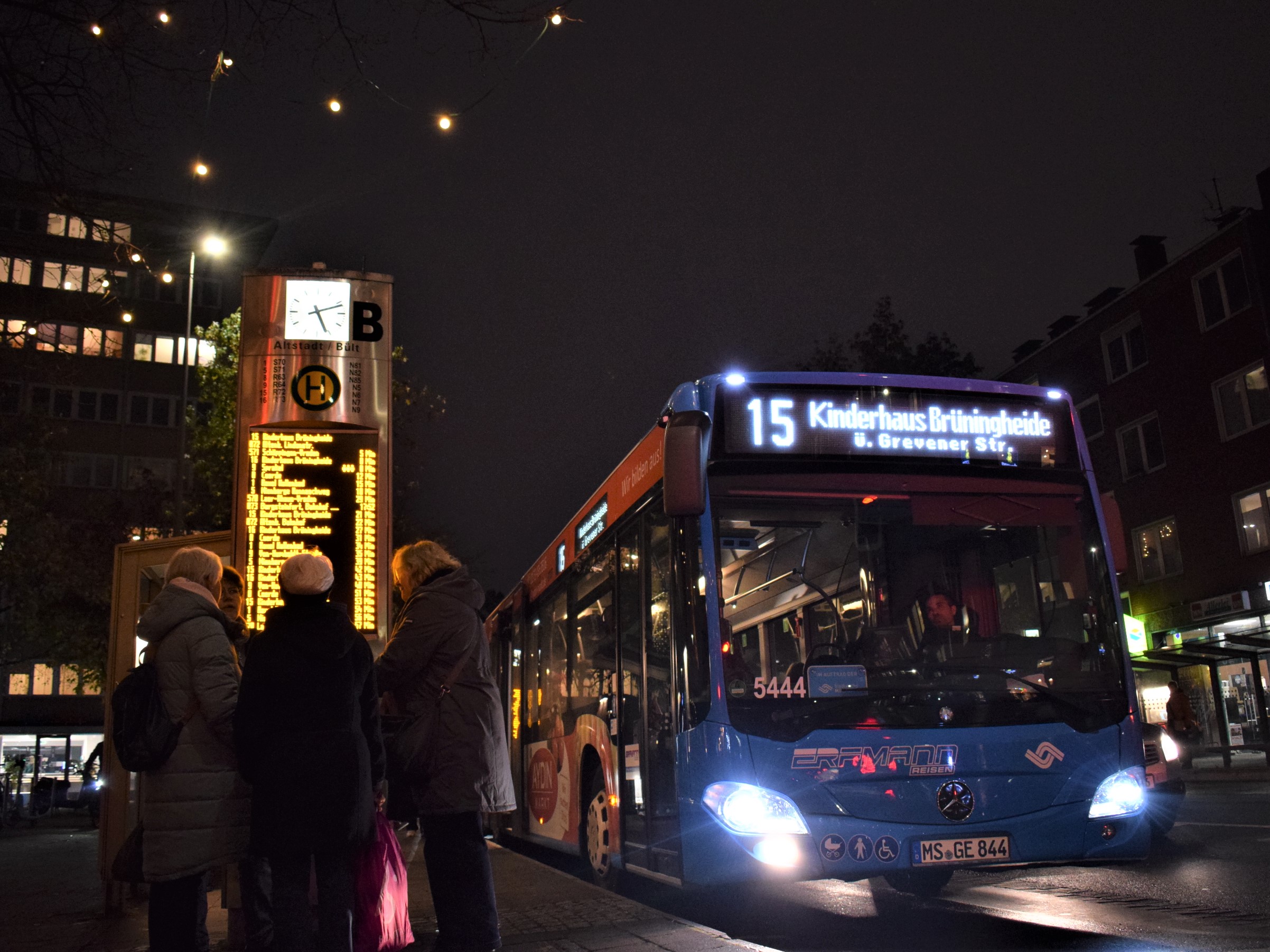 Eine Bushaltestelle bei Dunkelheit, ein Bus hält gerade an