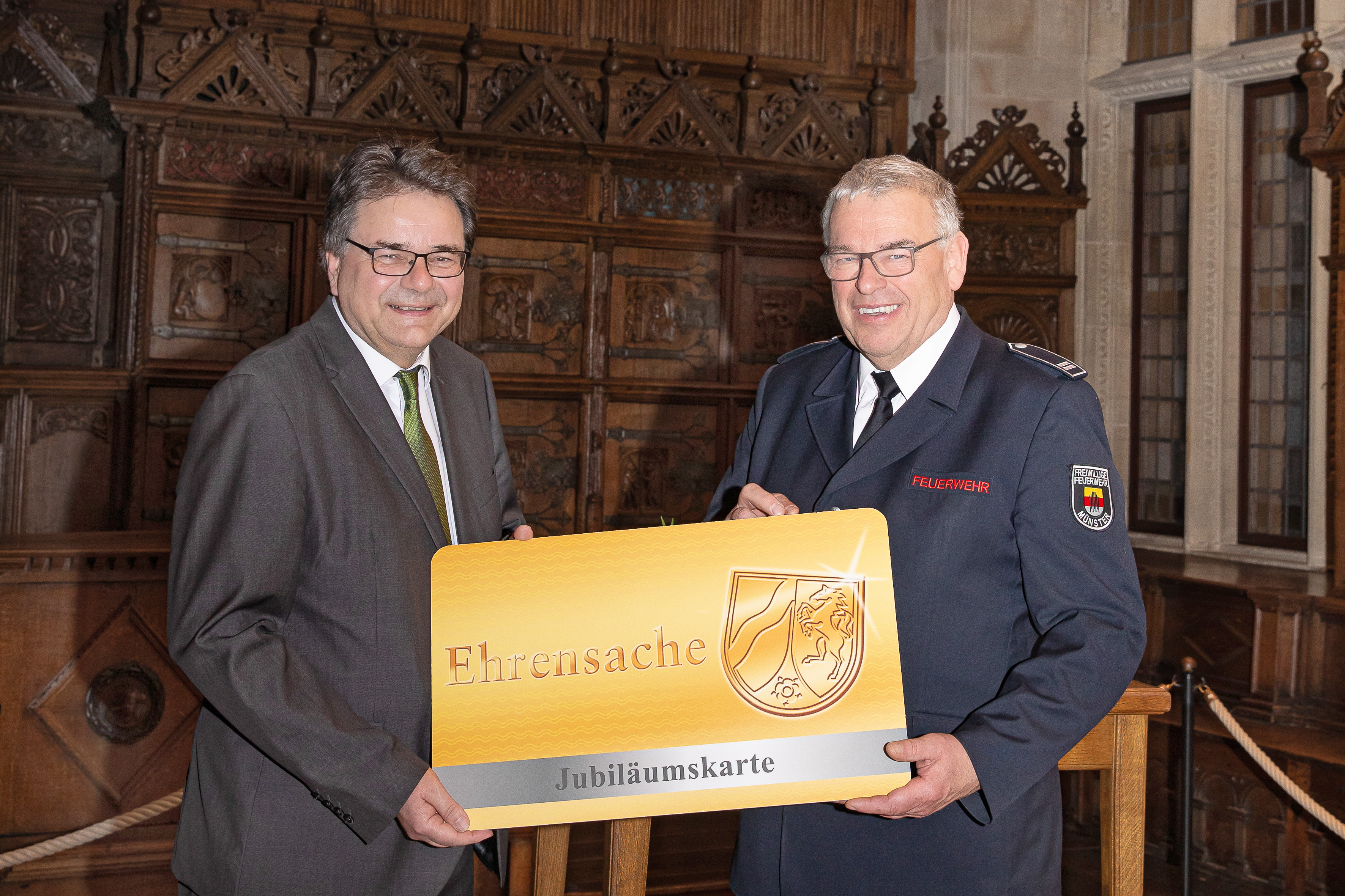 Bürgermeister Klaus Rosenau die 100. Jubiläums-Ehrenamtskarte an Georg Böckers von der Freiwilligen Feuerwehr Münster.