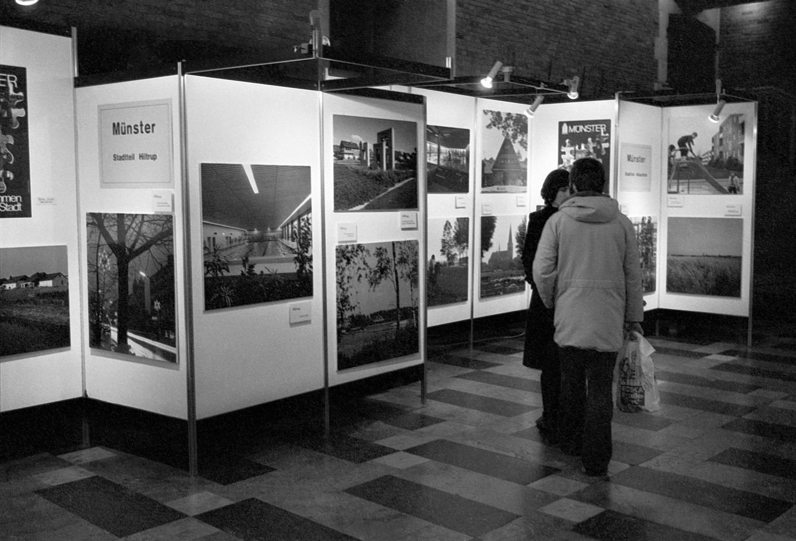Zwei Personen schauen sich Bilder auf der Ausstellung zur Gebietsreform 1975 an, in schwarz weiß