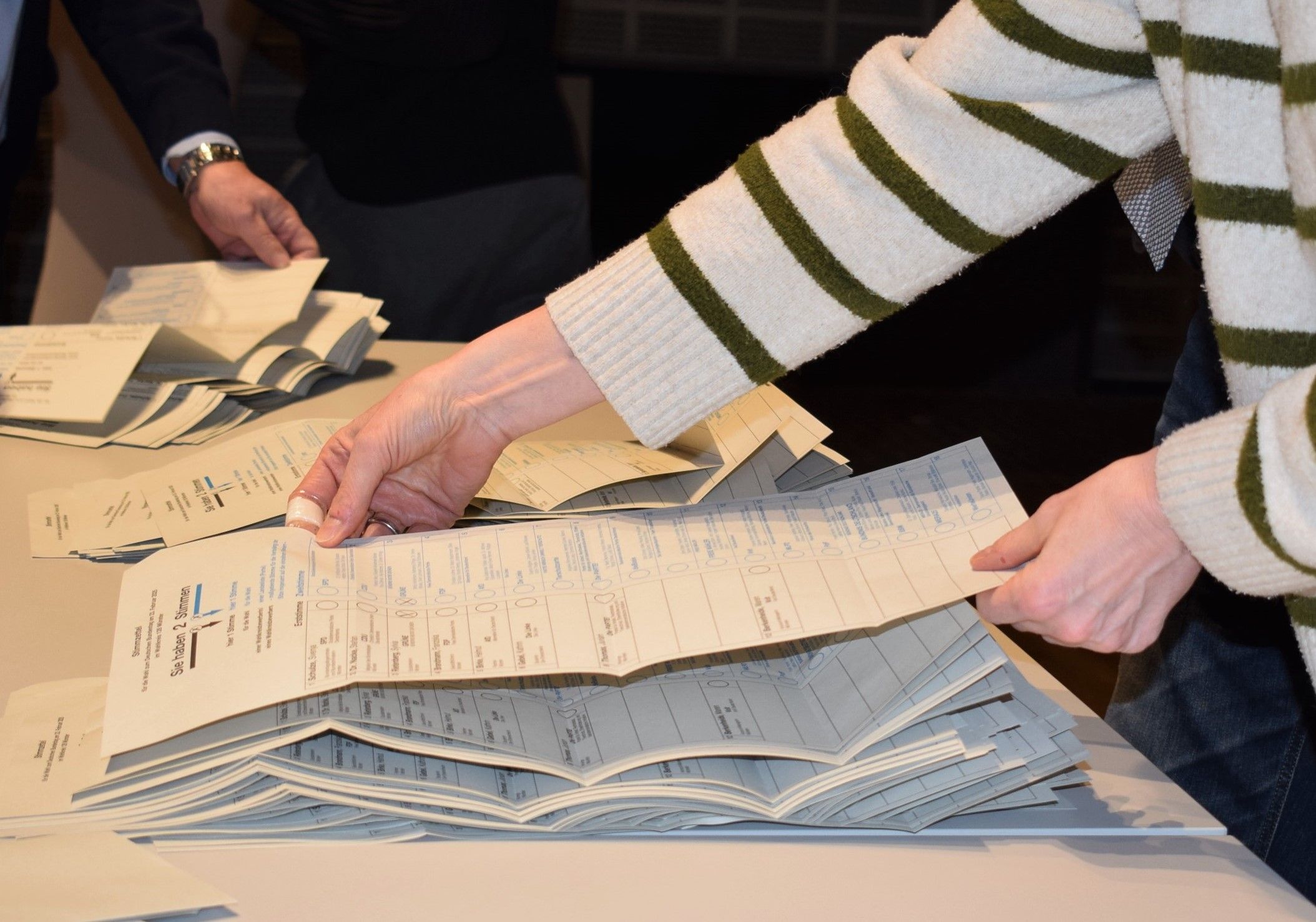 Mehrere Hände auf Stapeln von Wahlzetteln