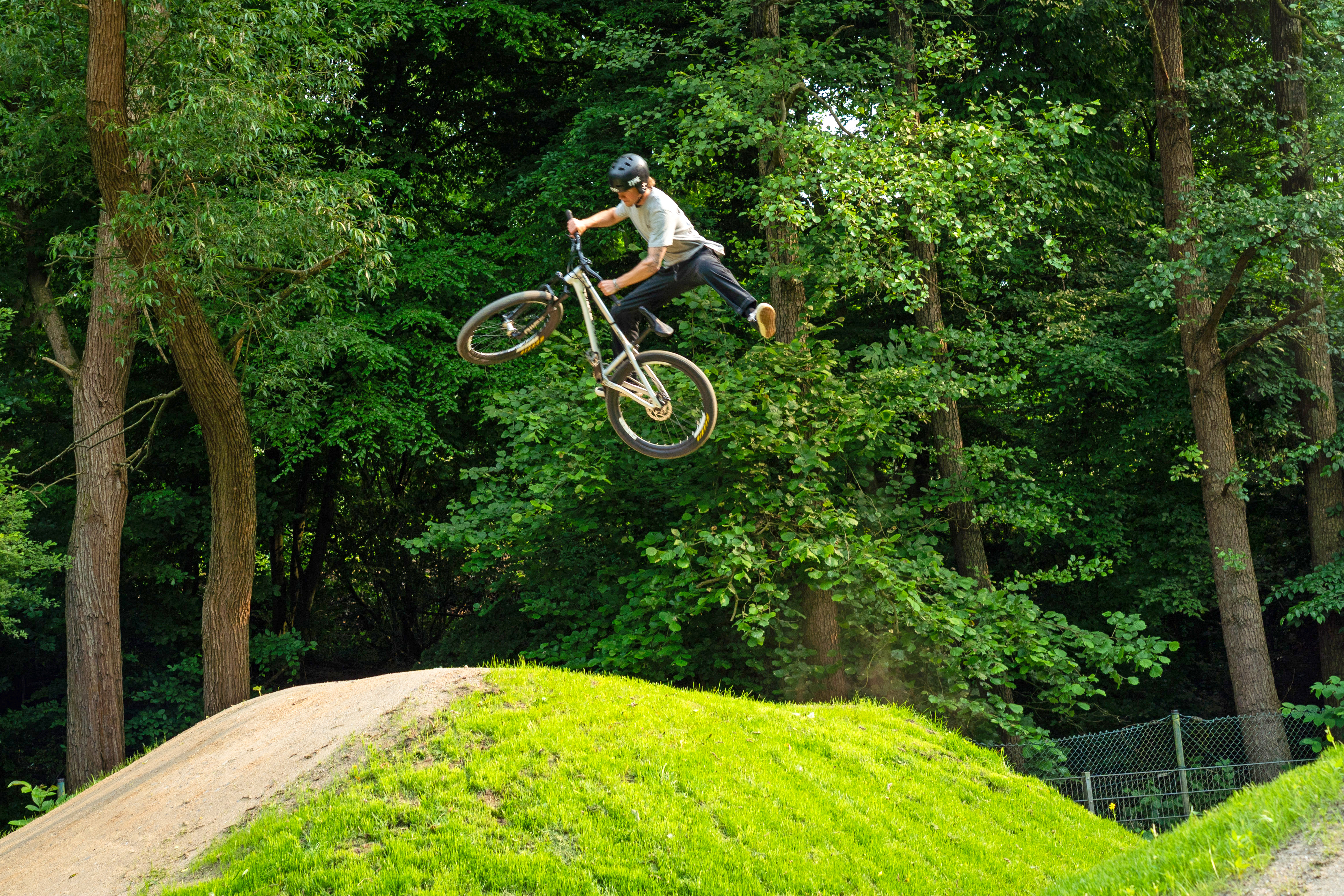 Jugendlicher auf dem Fahrrad springt hoch in die Luft auf der Dirtbike-Anlage
