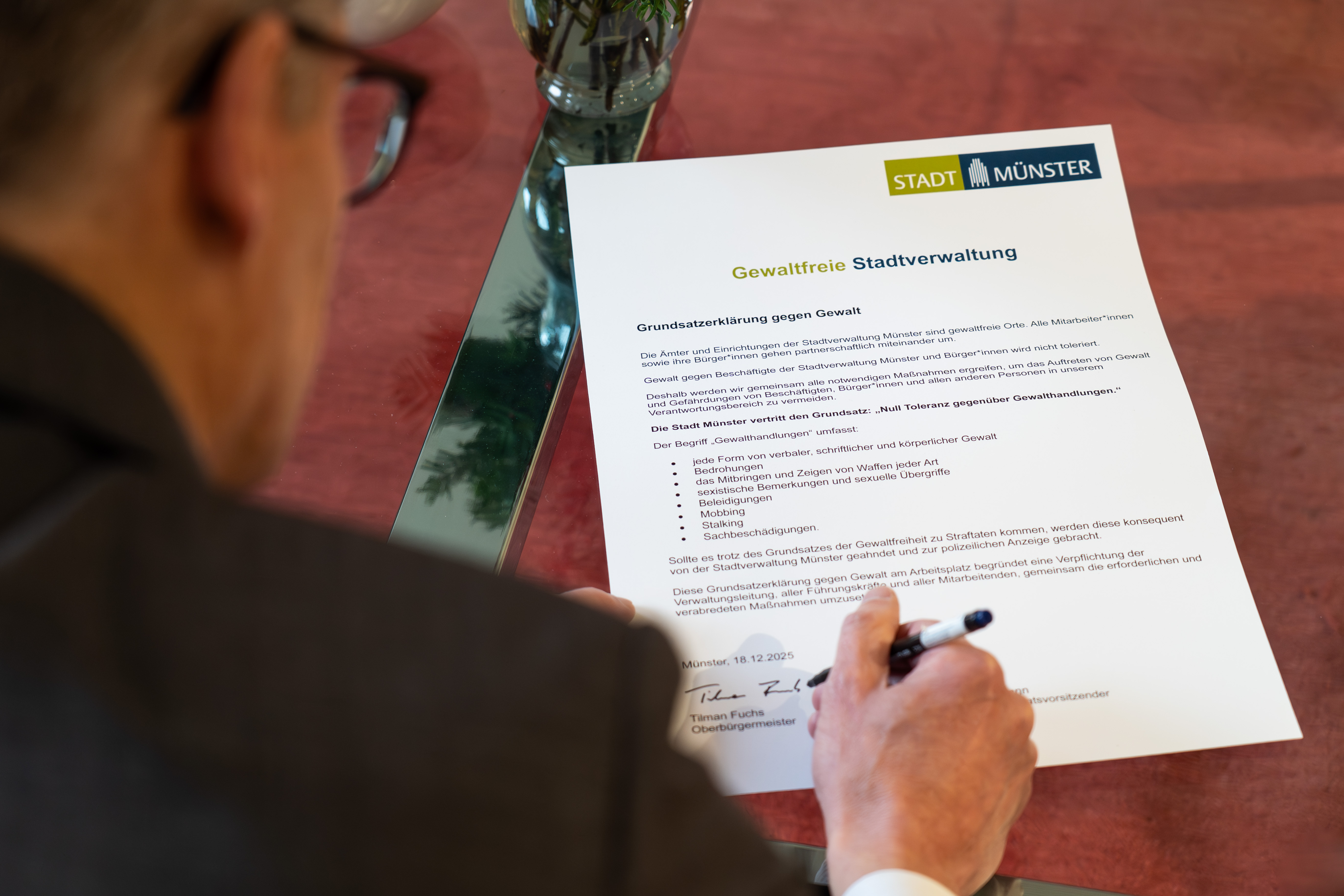 Blick auf die unterschreibende Hand auf dem Papier