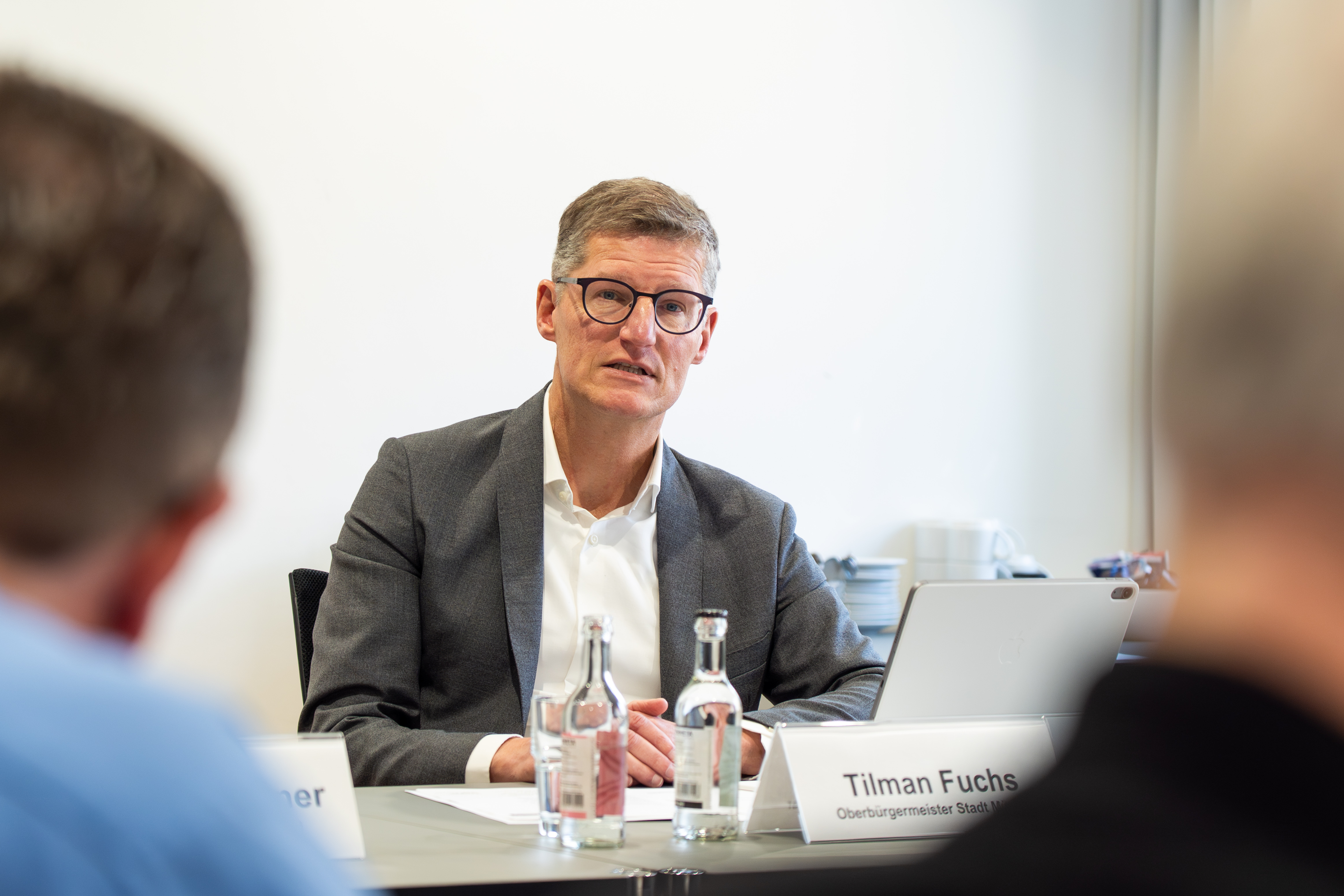 Ein Mann sitzt an einem Tisch, ihm gegenüber zwei Personen, die nicht deutlich zu sehen sind.