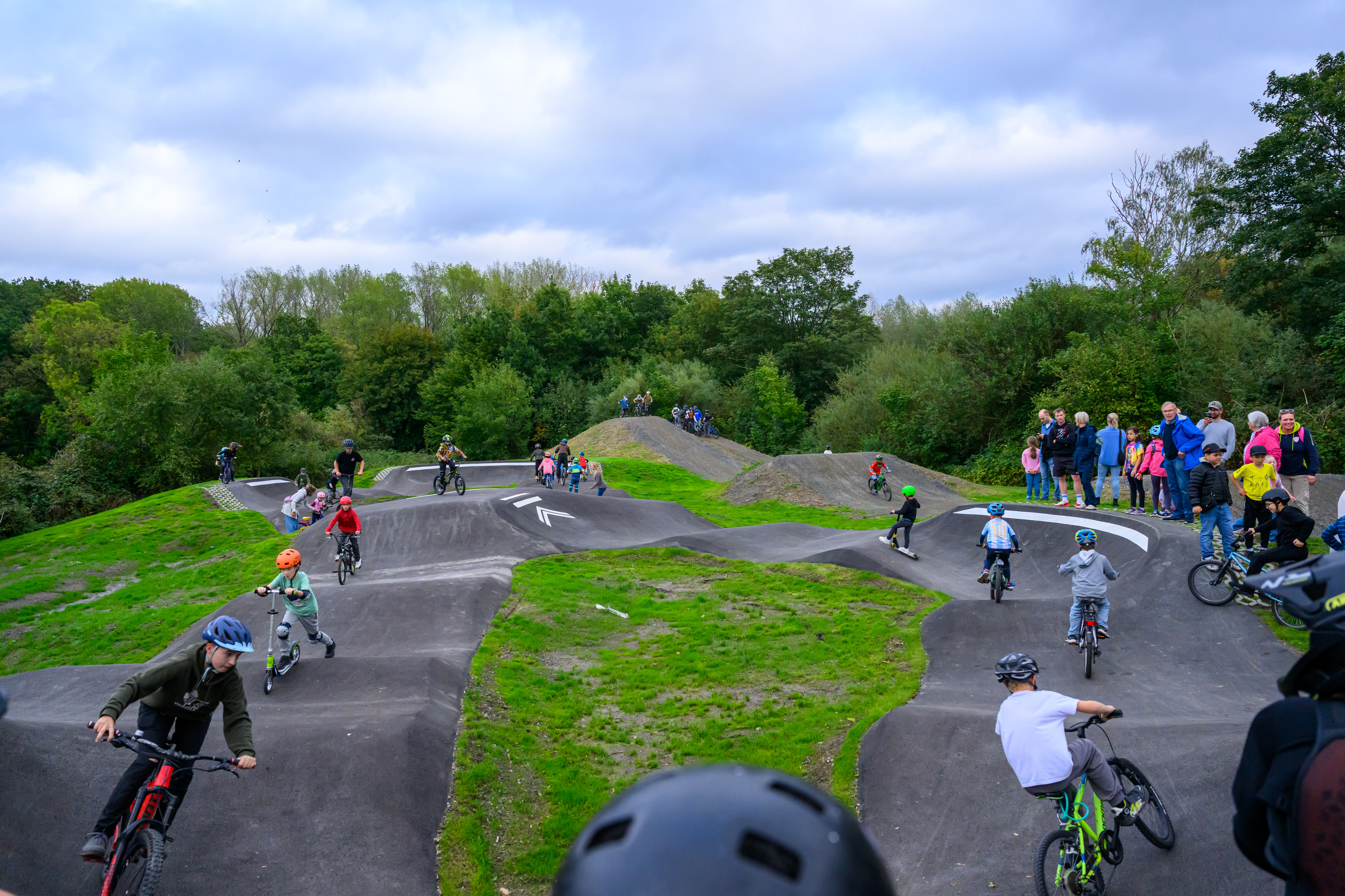 Kinder und Jugendliche fahren mit Rädern und Rollern auf der Skate-Bike-Anlage