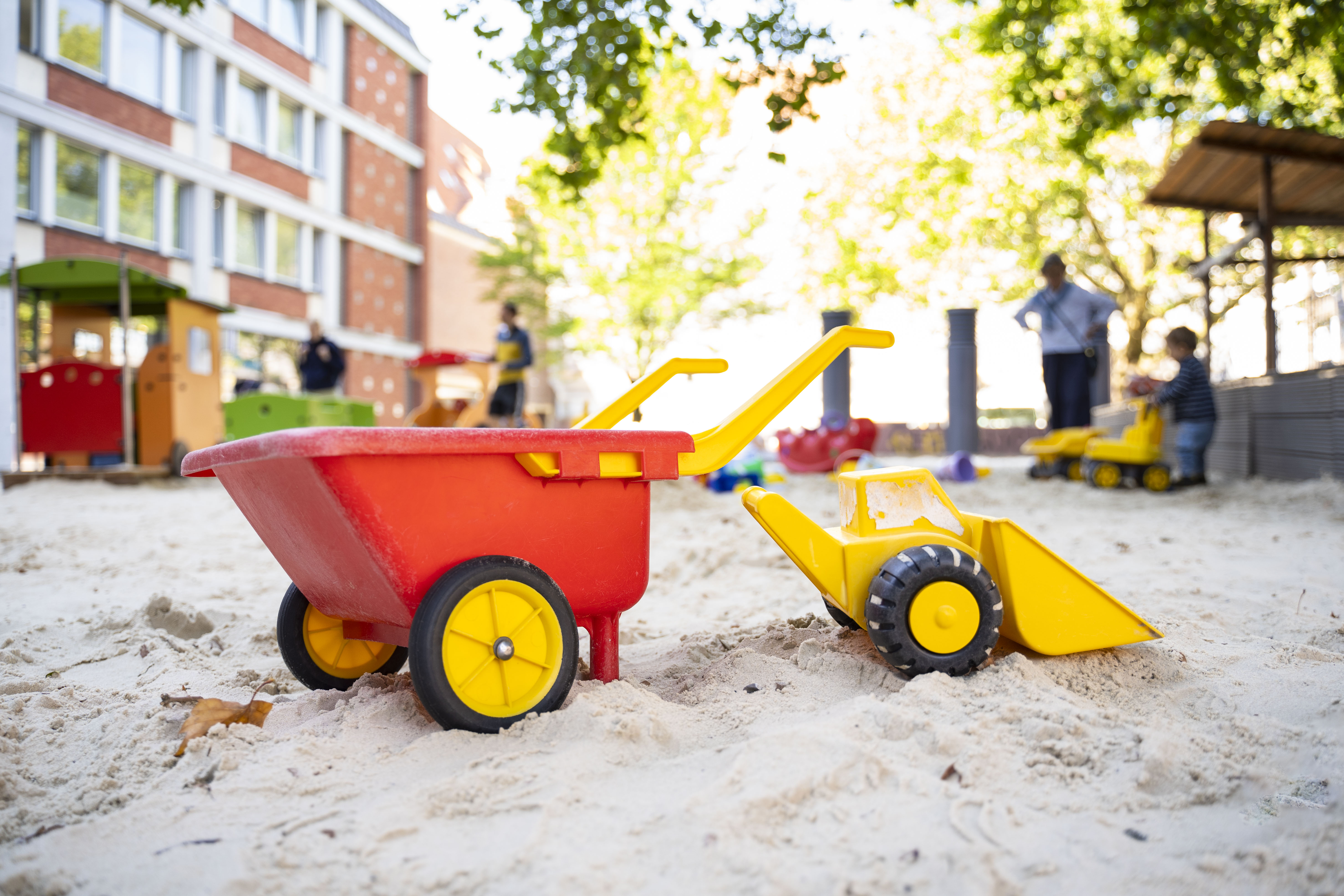Spielzeugbagger und -schubkarre im Sandkasten