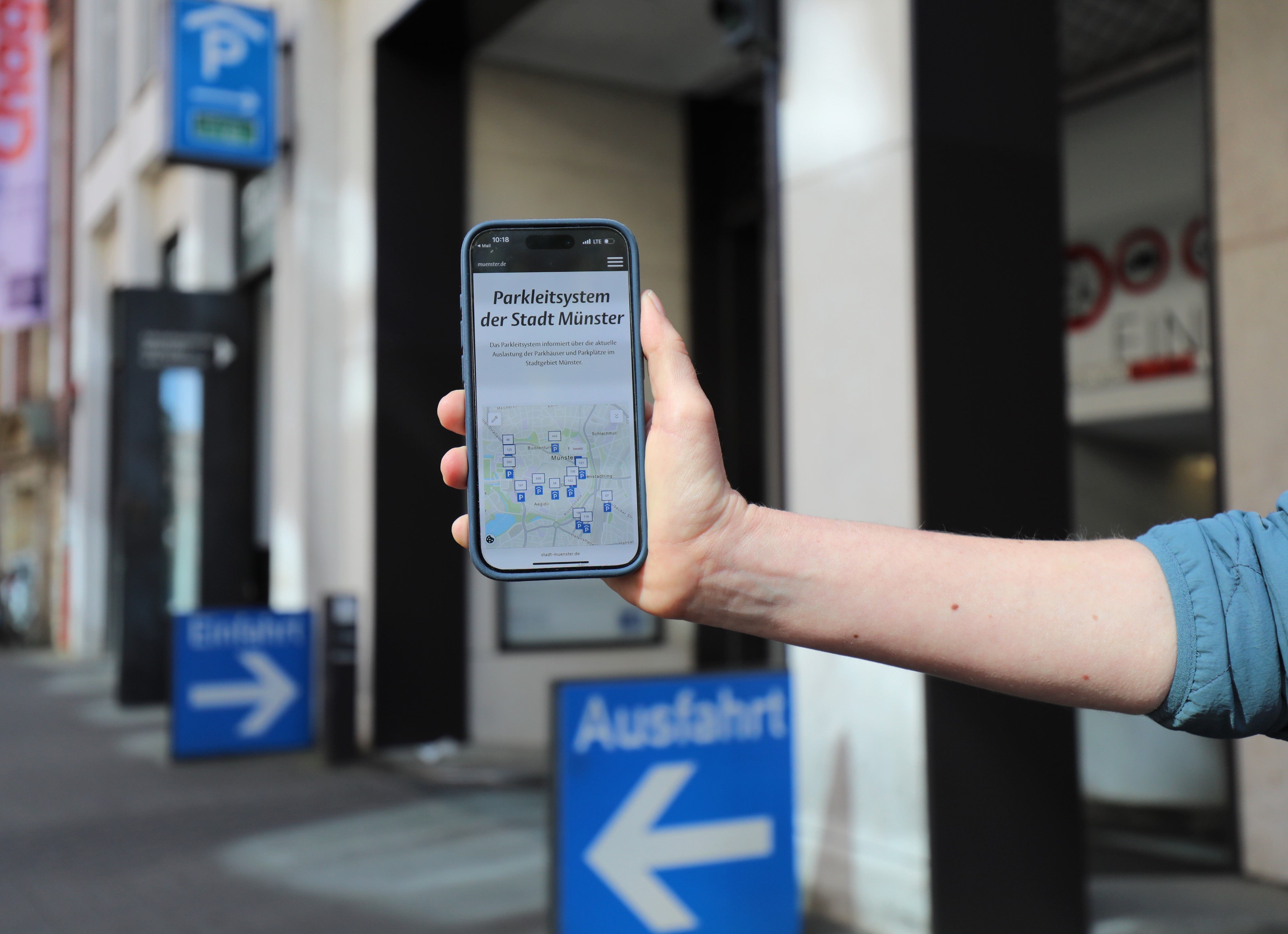 Smartphone in einer Hand, das das Parkleitsystem zeigt