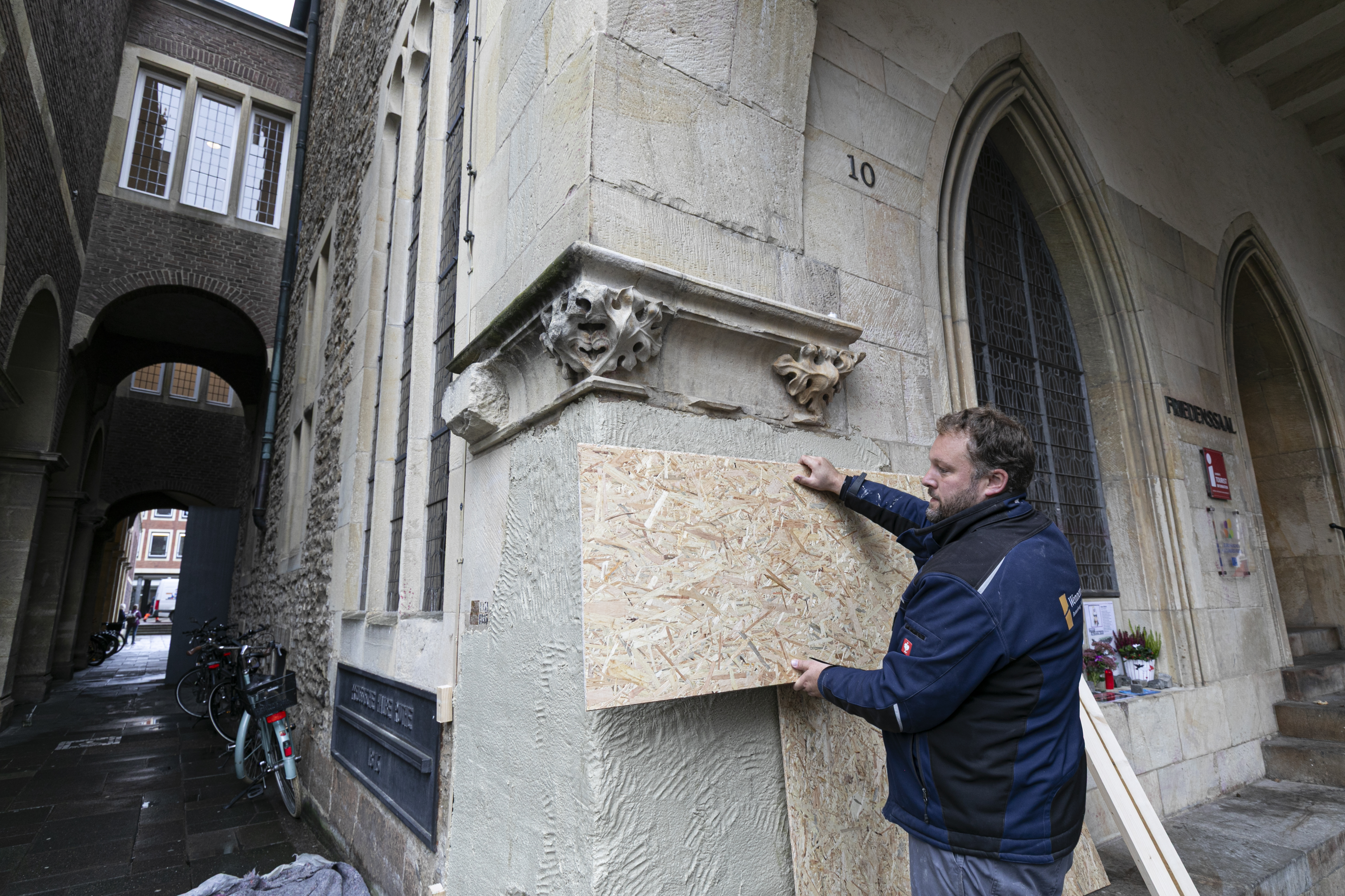Ein Arbeiter montiert Holzwände über die Kompressenmasse an der Fassade.