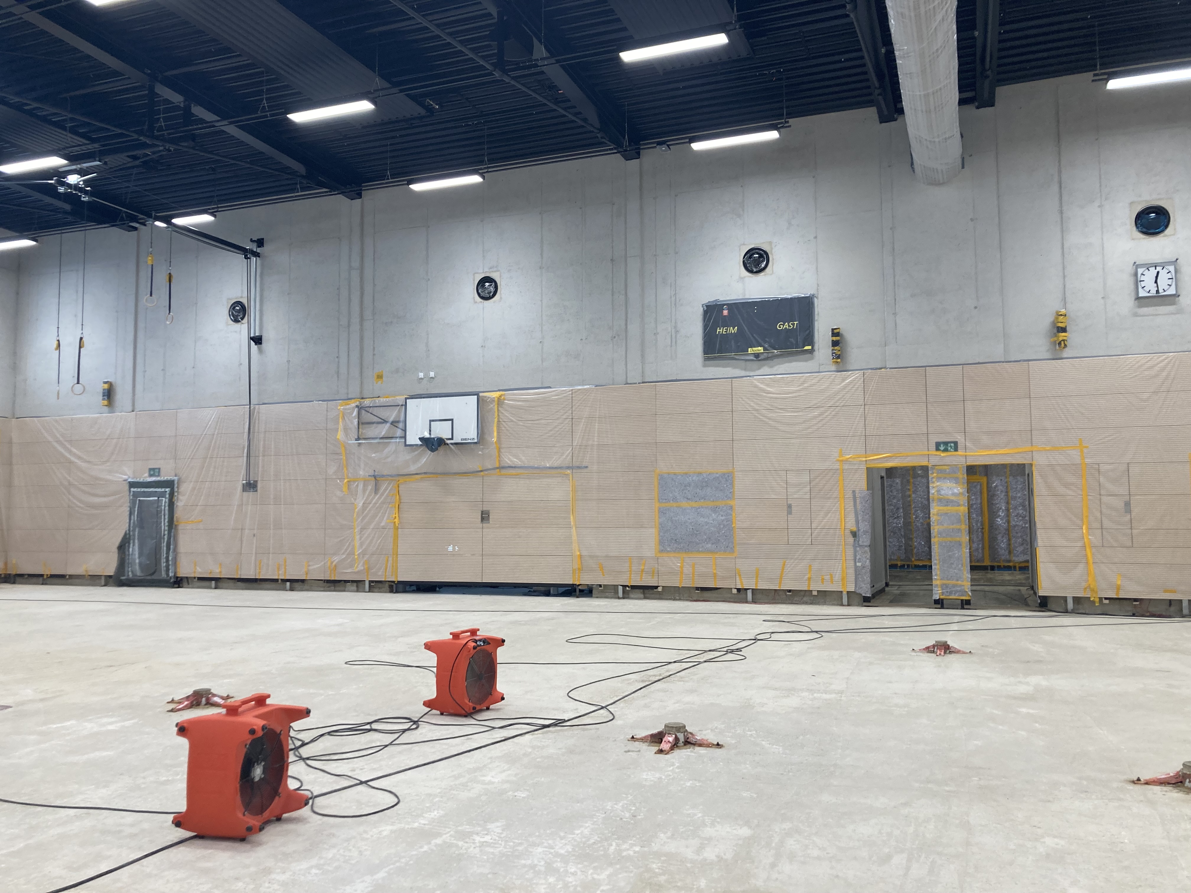 Blick auf eine Turnhallenwand mit mit Folie abgedeckten Holzelementen